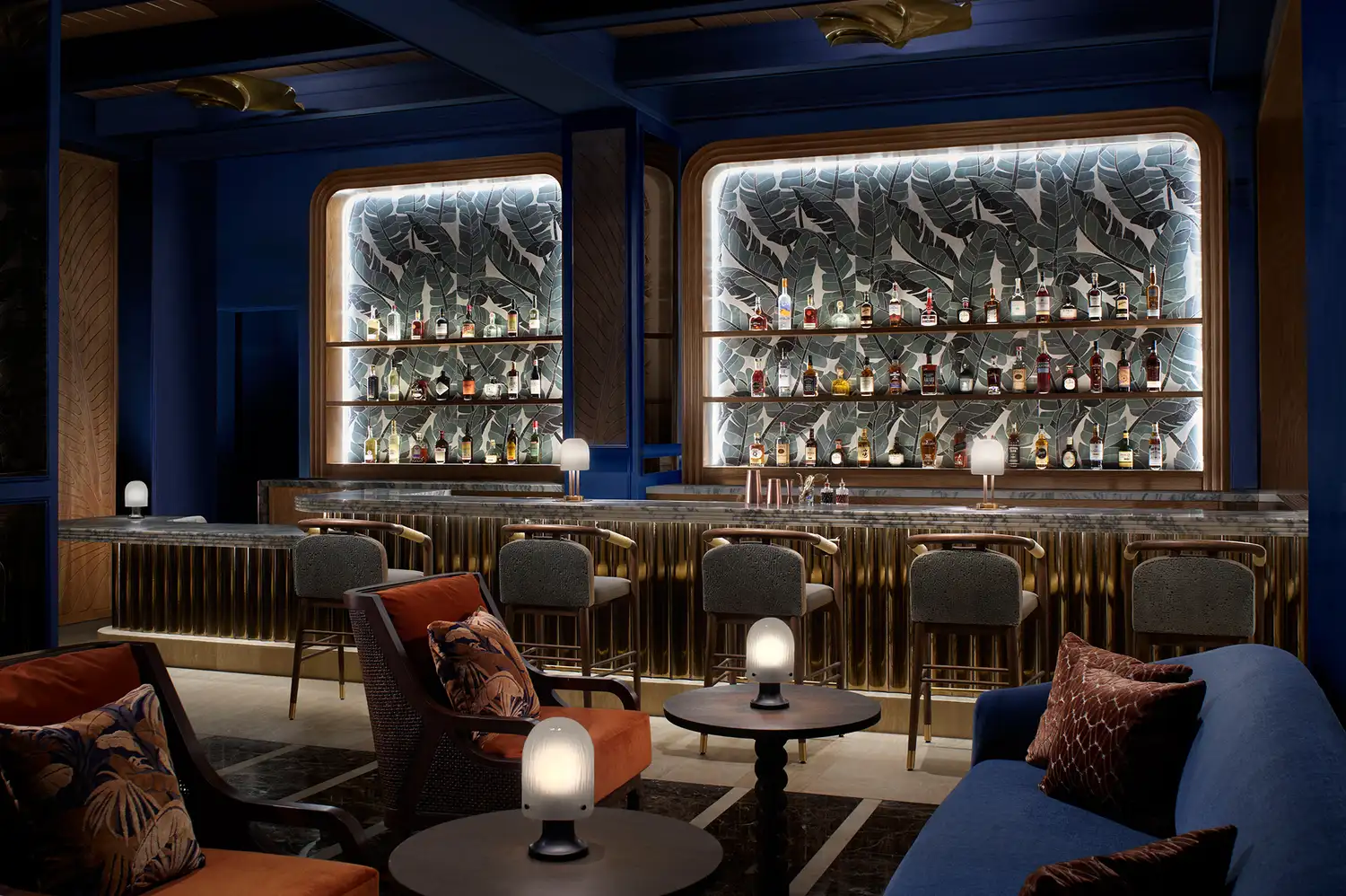 Sophisticated bar area with back-lit shelving, dark countertops, and elegant seating.