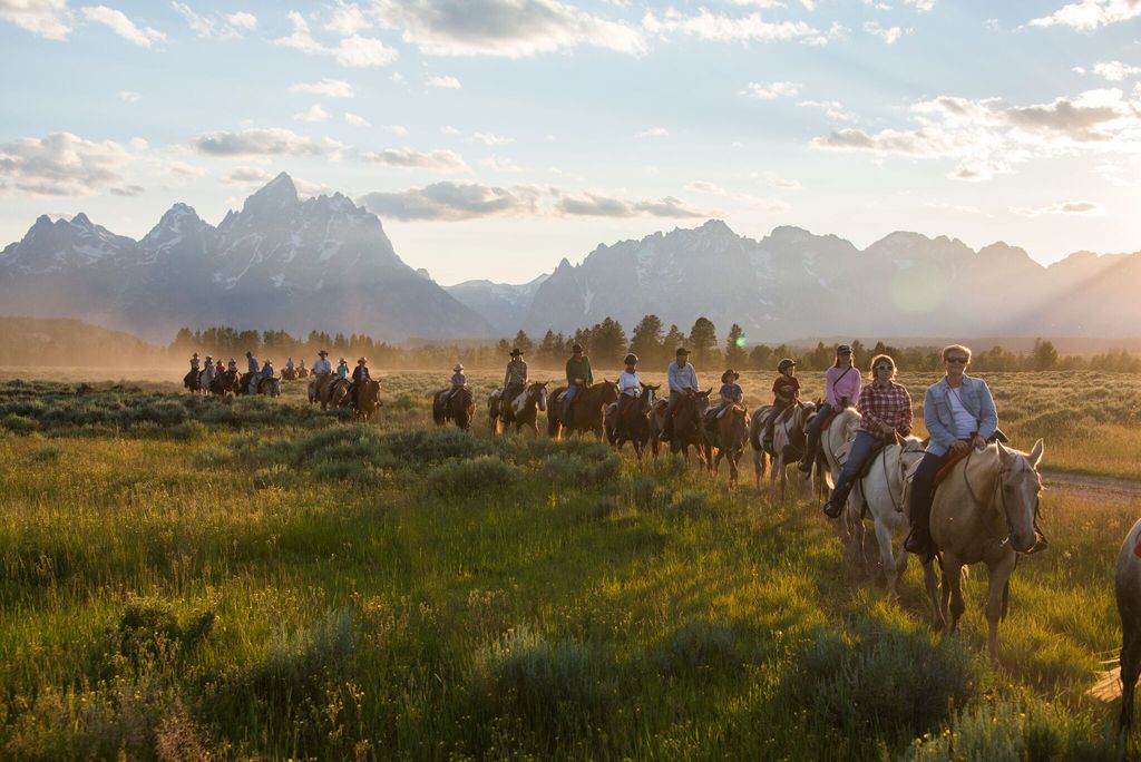 Visitors horseback riding at Triangle X Ranch with the Teton mountains in the background.