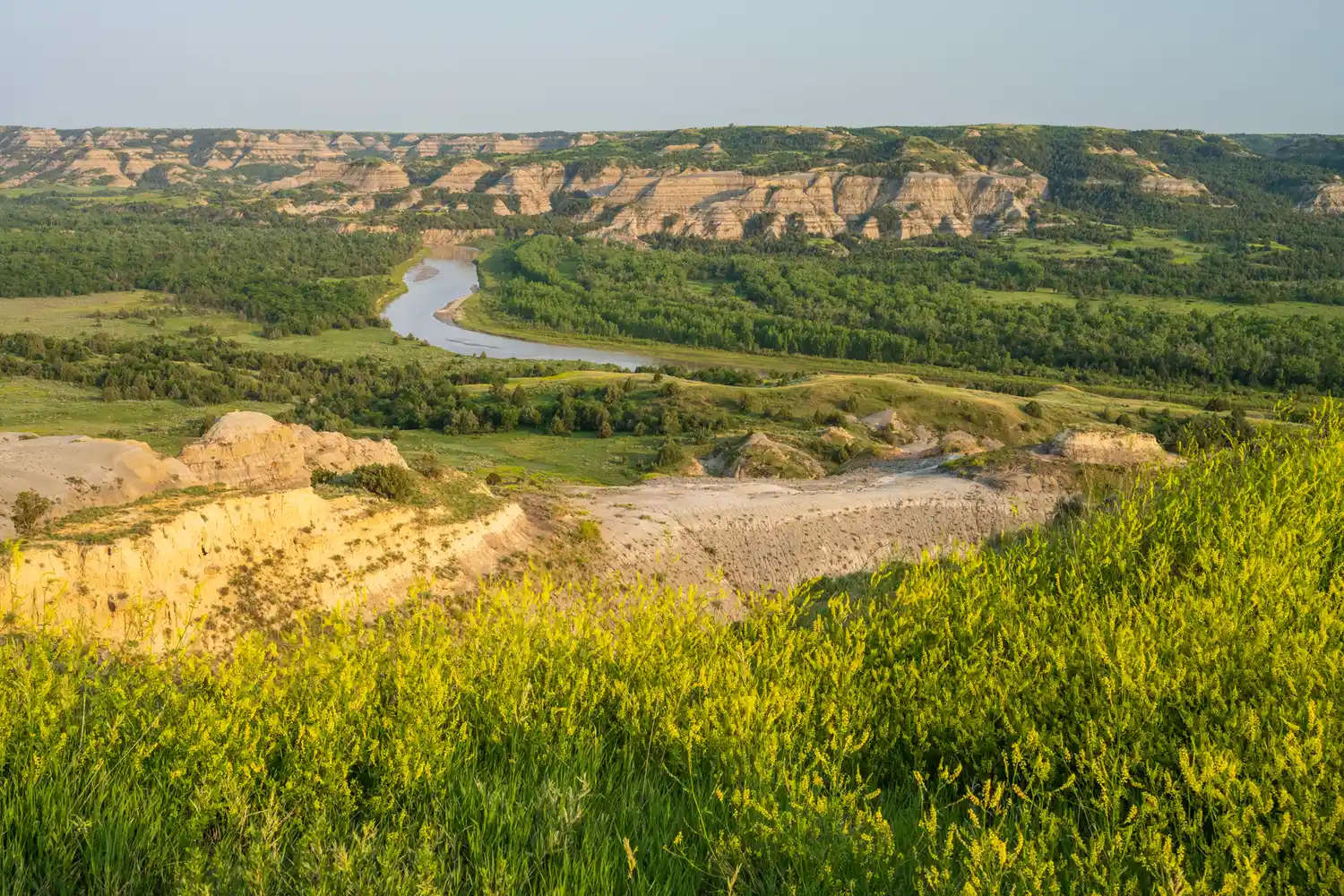 High-angle view of the Little Missouri River curving sharply through a deep valley surrounded by forested slopes.