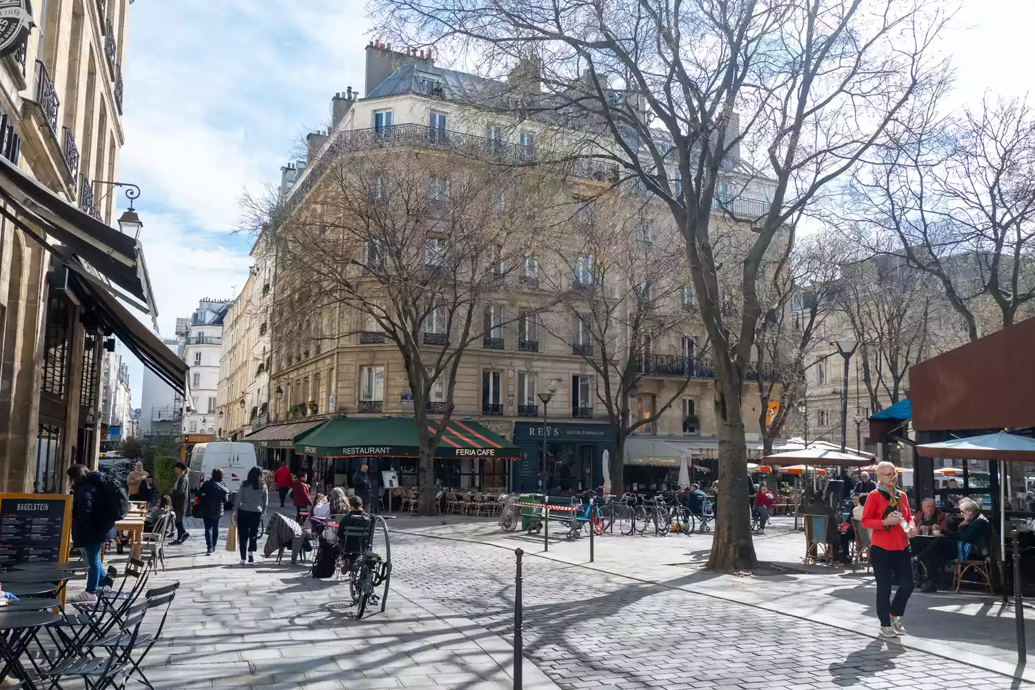 Sunlit restaurant terraces and patios in the Marais district of Paris.