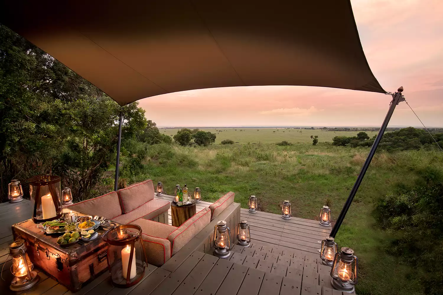 A luxurious guest room at andBeyond Bateleur Camp in Kenya featuring expansive windows with a view of the savanna.