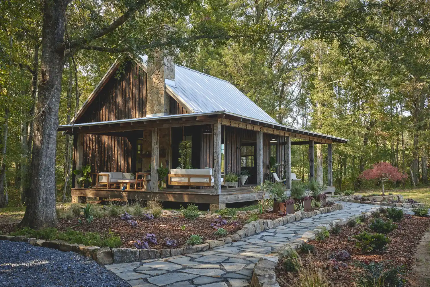 A rustic wooden cabin with a landscaped stone path in a forest setting.