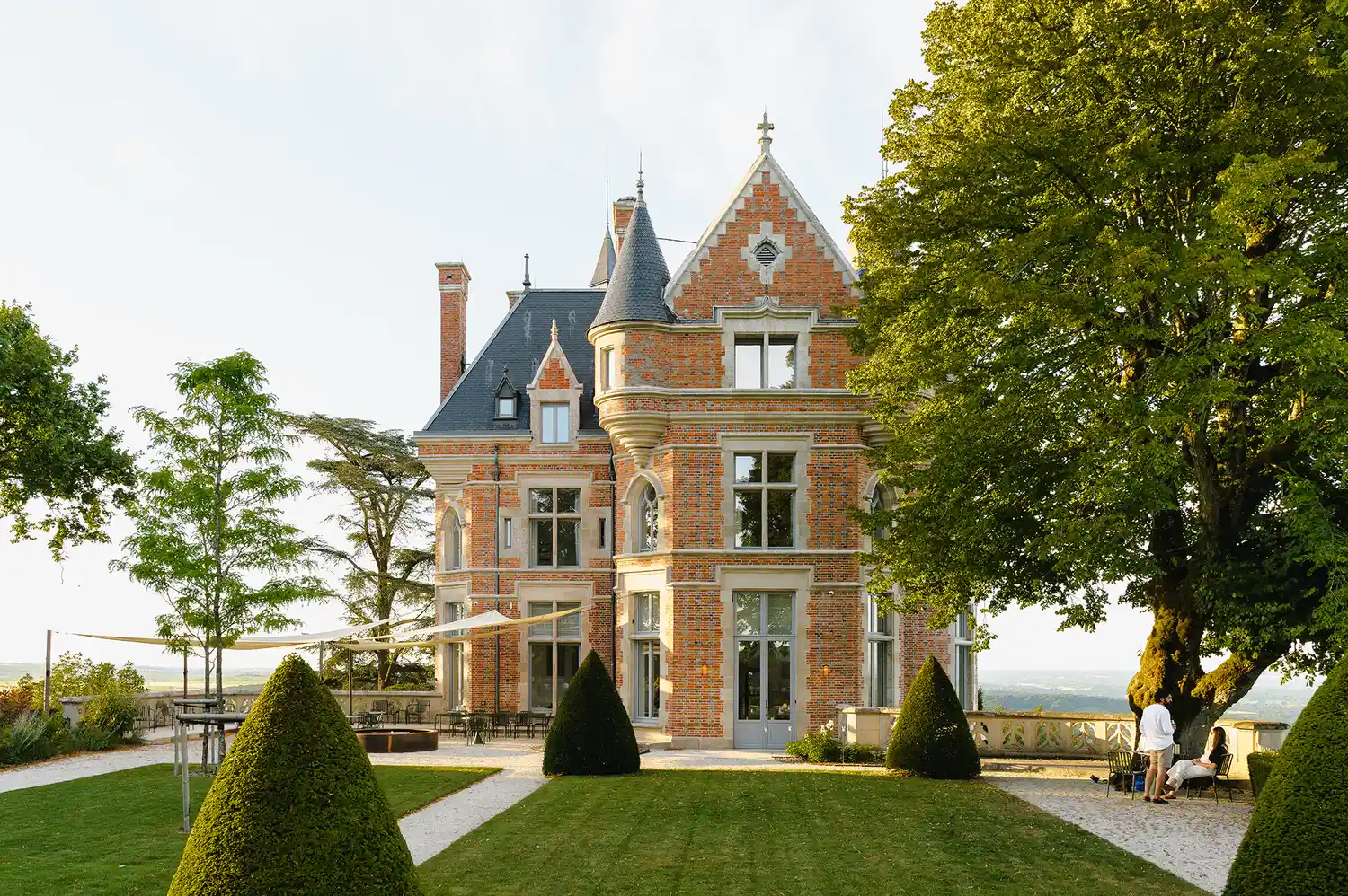 A historic stone chateau surrounded by manicured gardens in the French countryside.