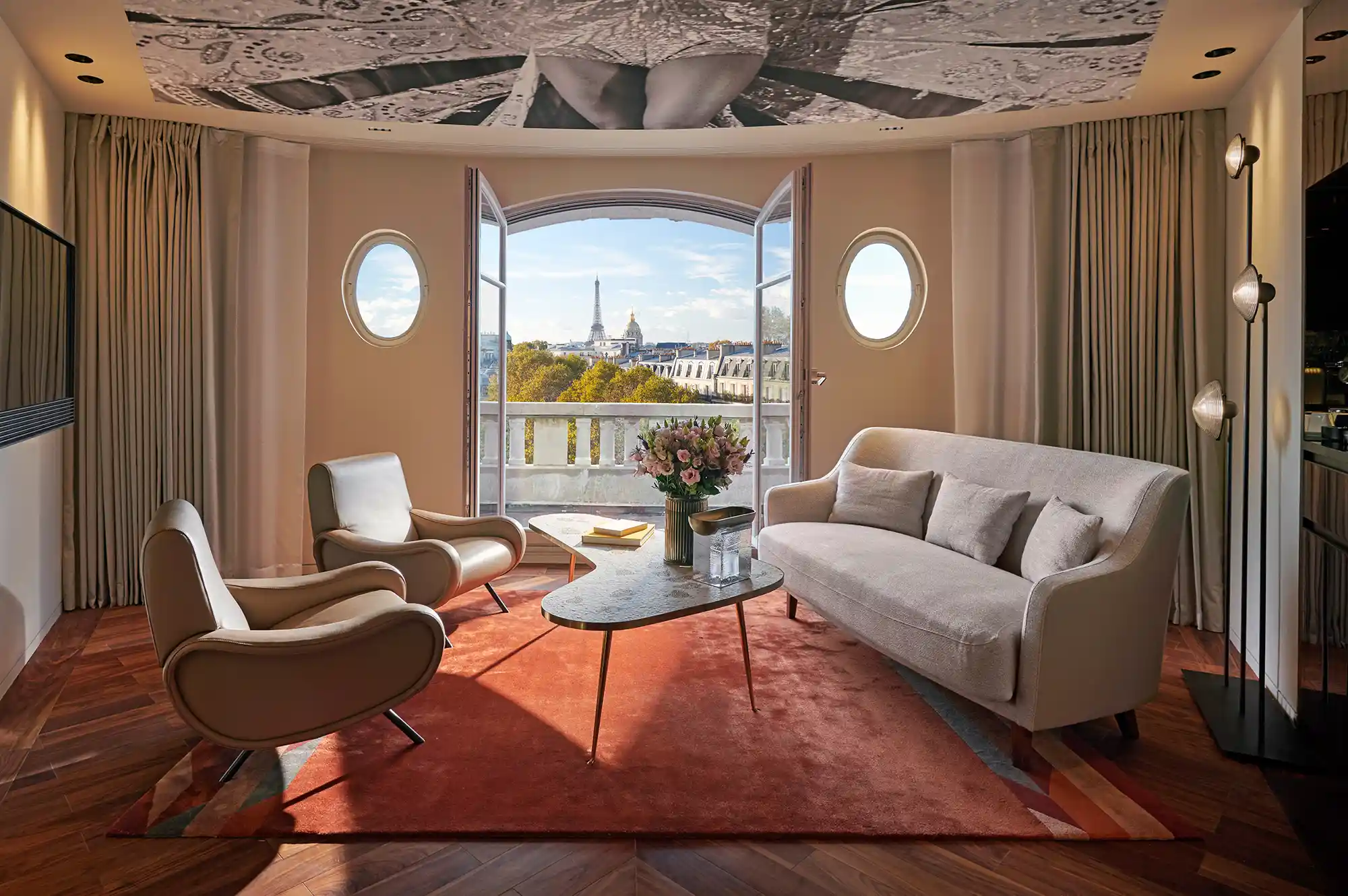 A luxury suite living room at Mandarin Oriental Lutetia with large windows overlooking the Eiffel Tower.