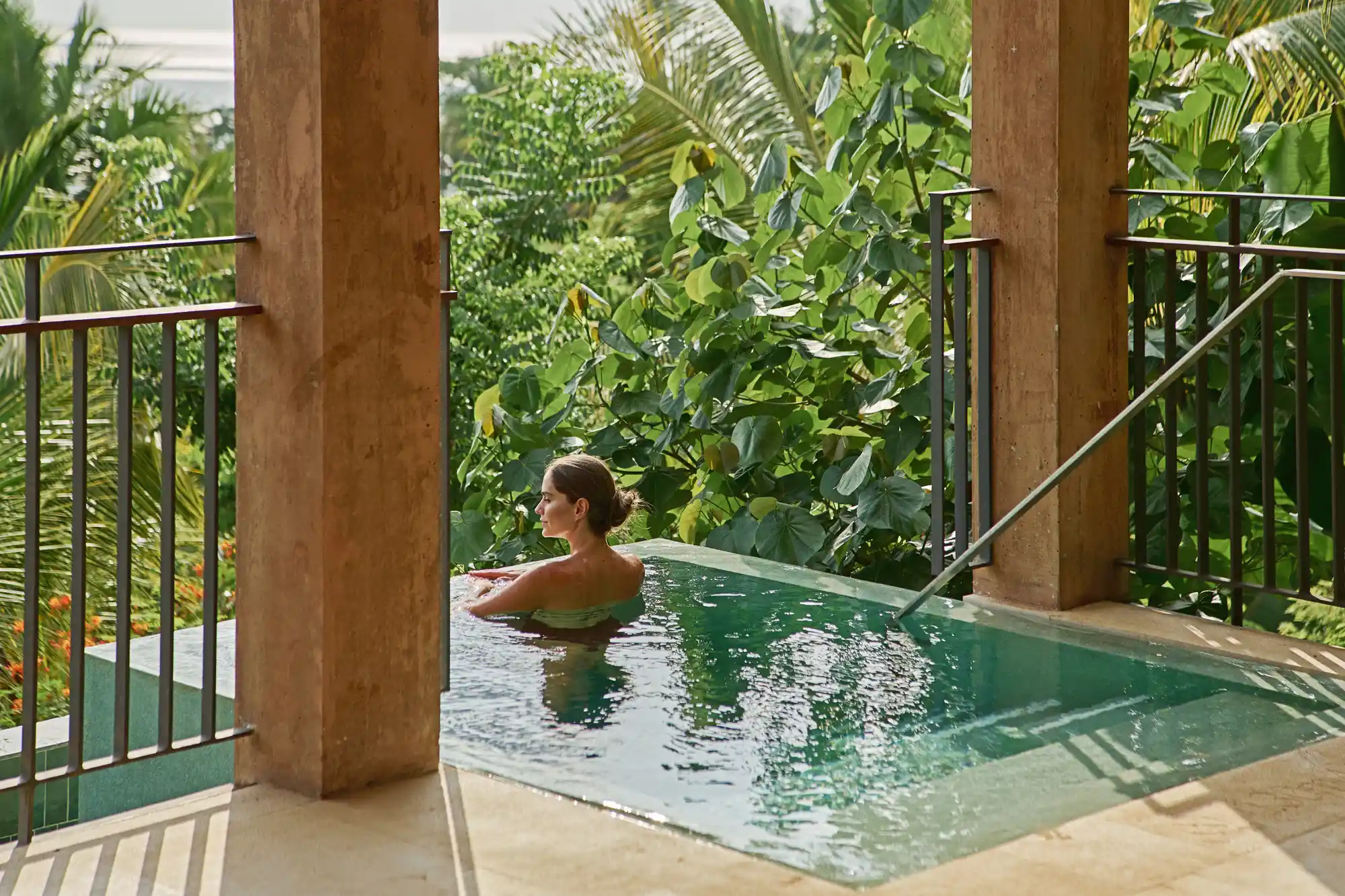 A guest relaxing in a private infinity pool overlooking lush tropical foliage.