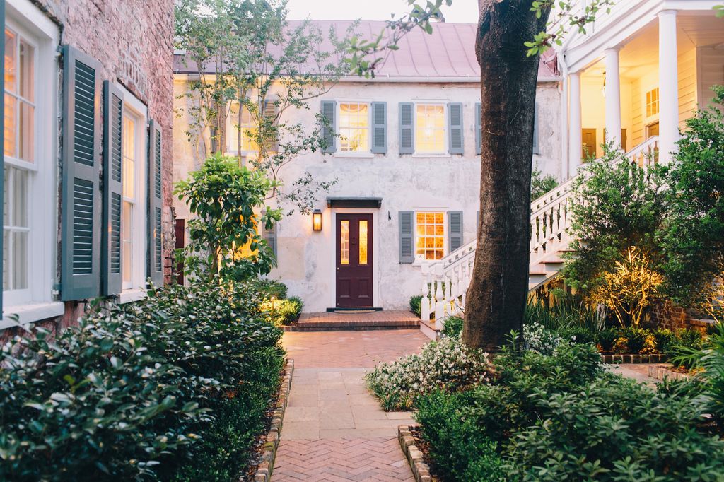 The historic brick exterior and lush green courtyard gardens of Zero George hotel in Charleston.