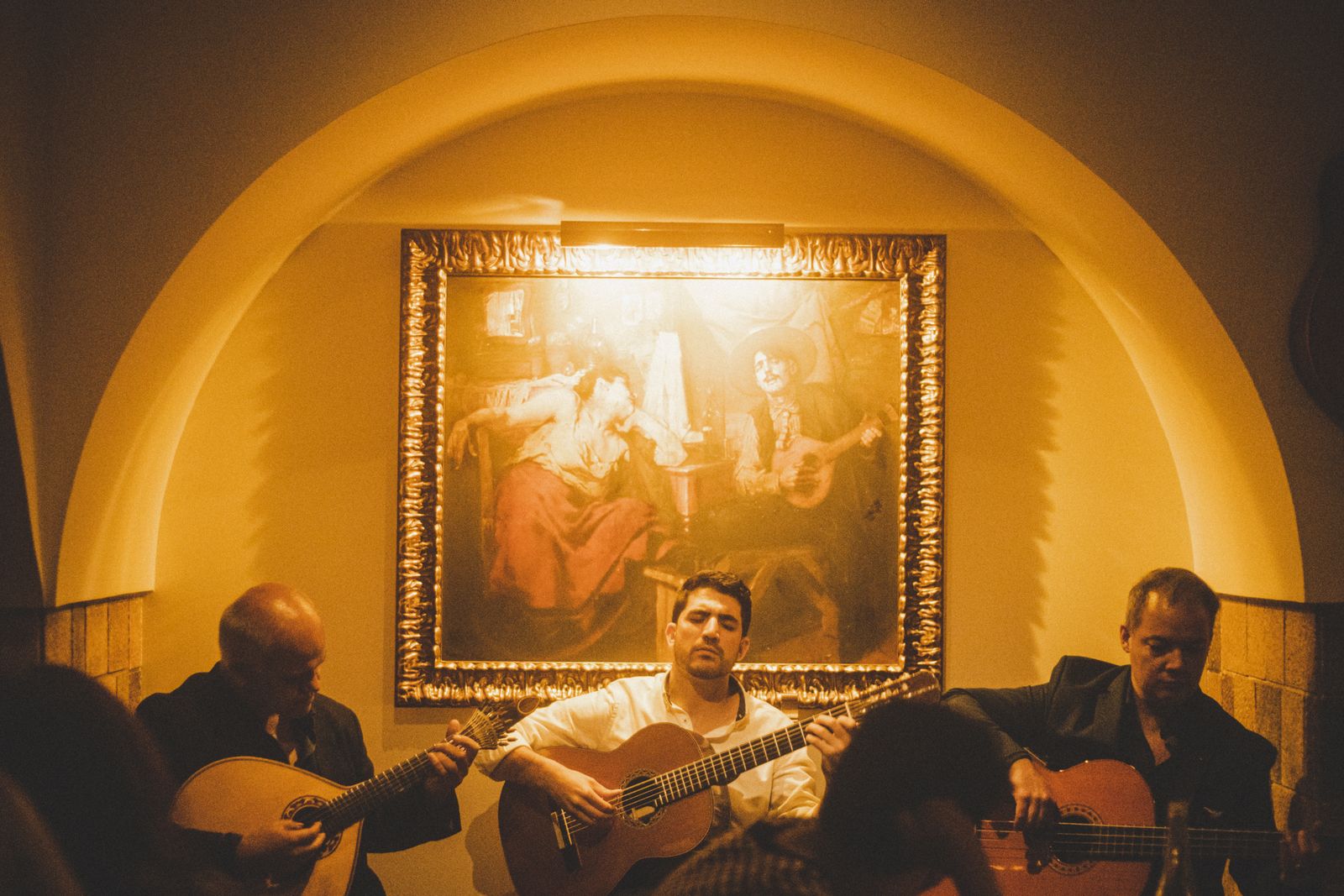 Close-up portrait of a Portuguese guitarist playing during a live Fado session.