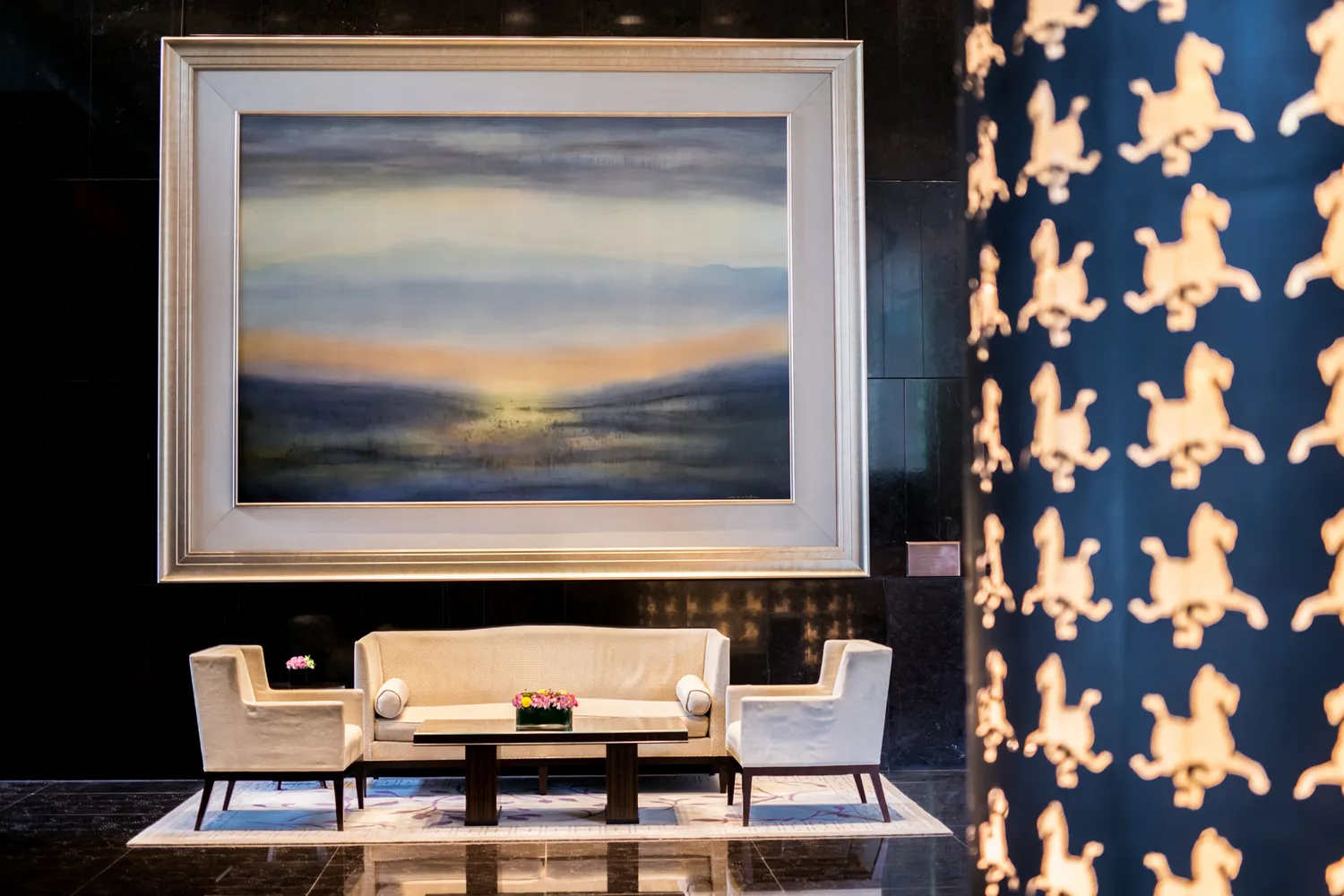 Elegant hotel lobby with beige seating, floral arrangements, and traditional artwork