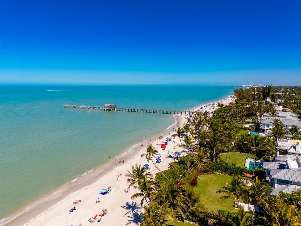 Wide shot of a powder-white sand beach and turquoise Gulf waters in Naples, Florida.