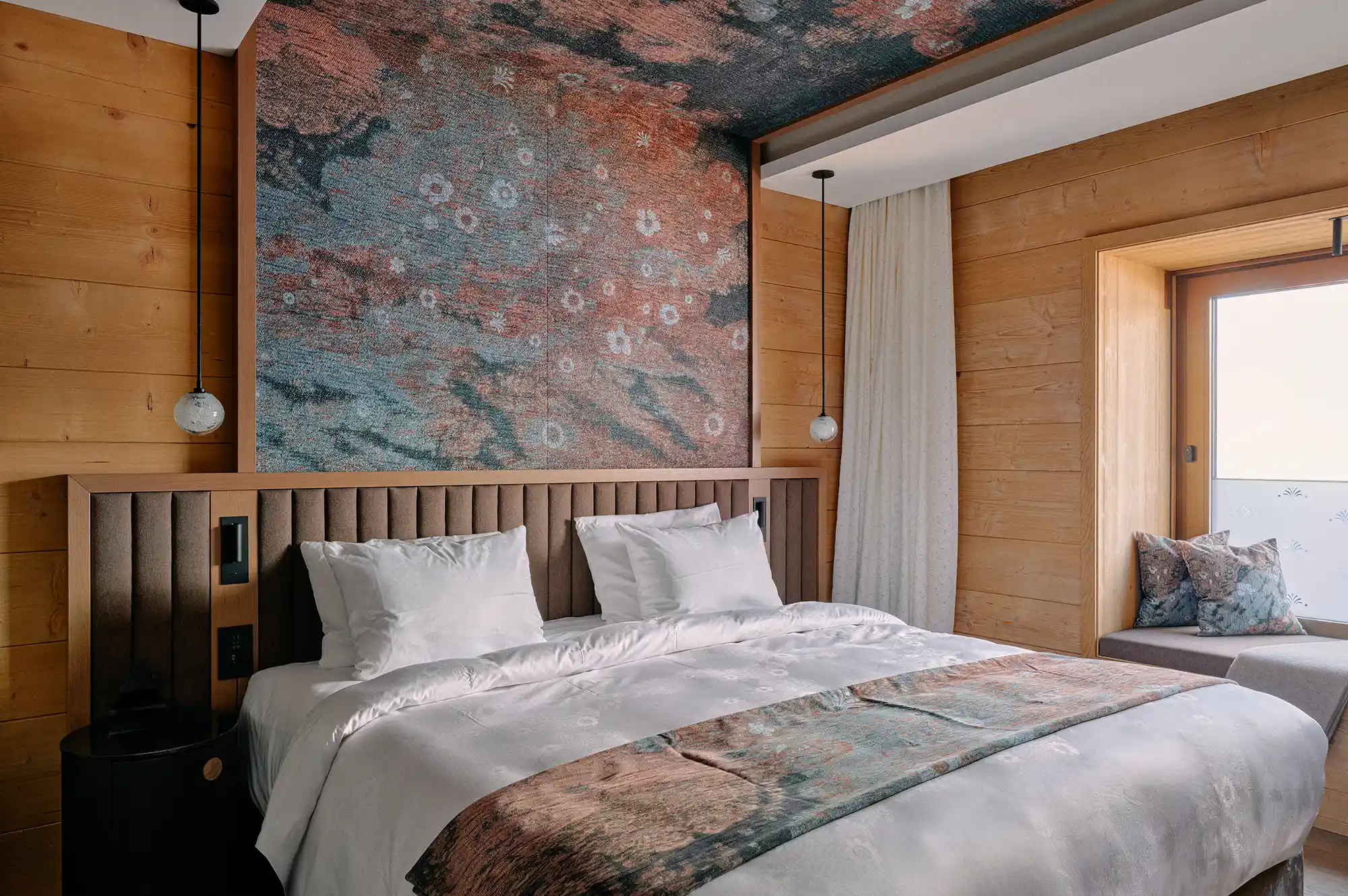 Luxury bedroom at Huus Quell with contemporary art on the ceiling and a built-in window seat.