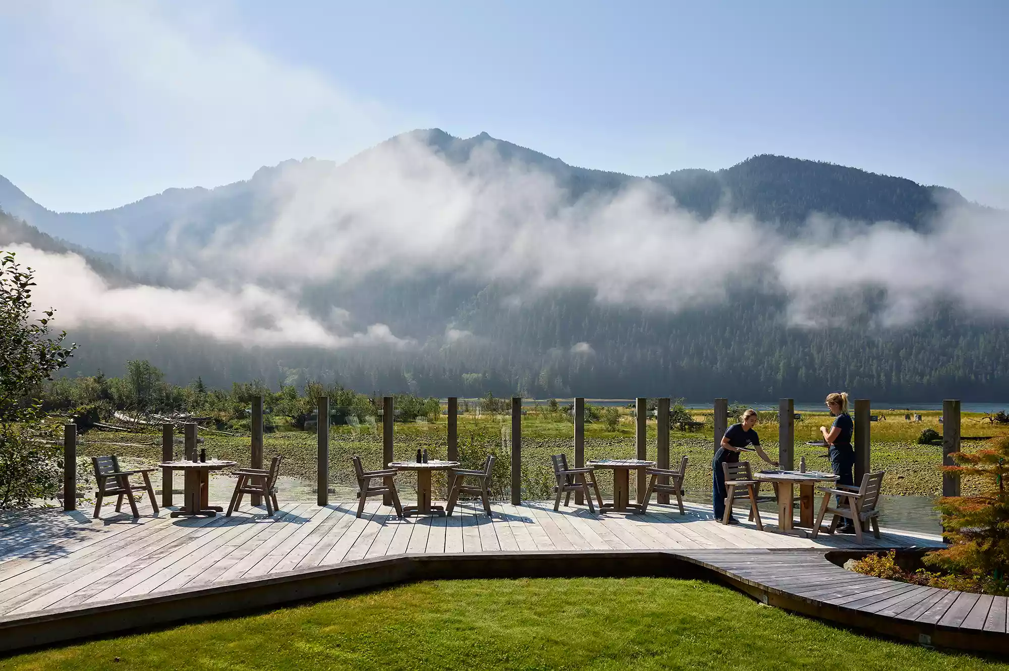 An elegantly set outdoor dining table overlooking the Bedwell River at Clayoquot Wilderness Lodge.