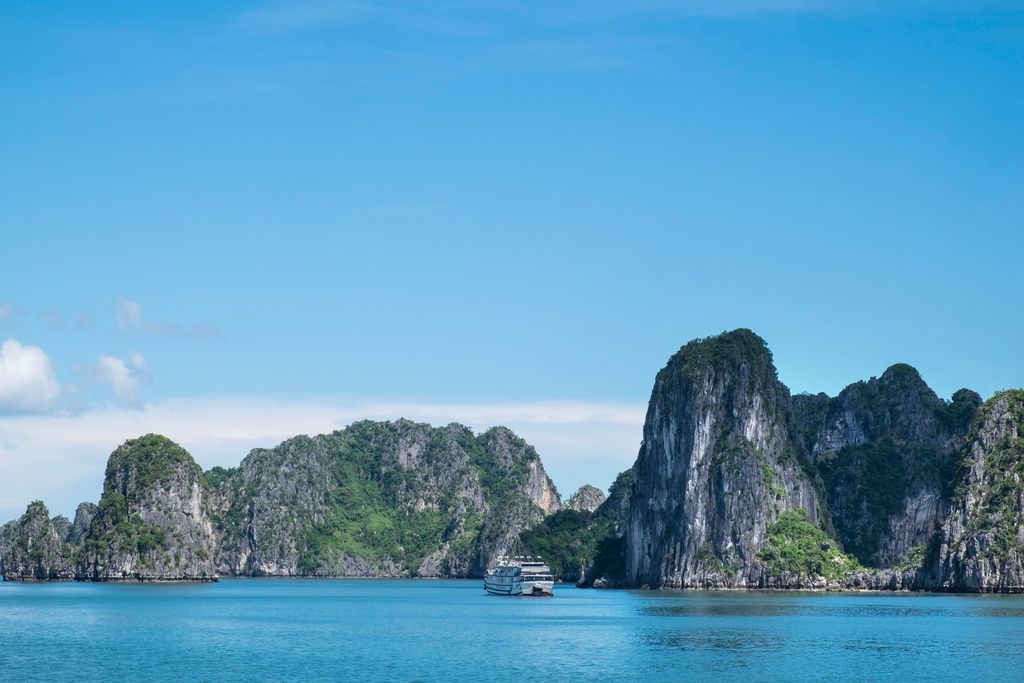 Traditional junk boats sailing among towering limestone karsts in the mist of Halong Bay.