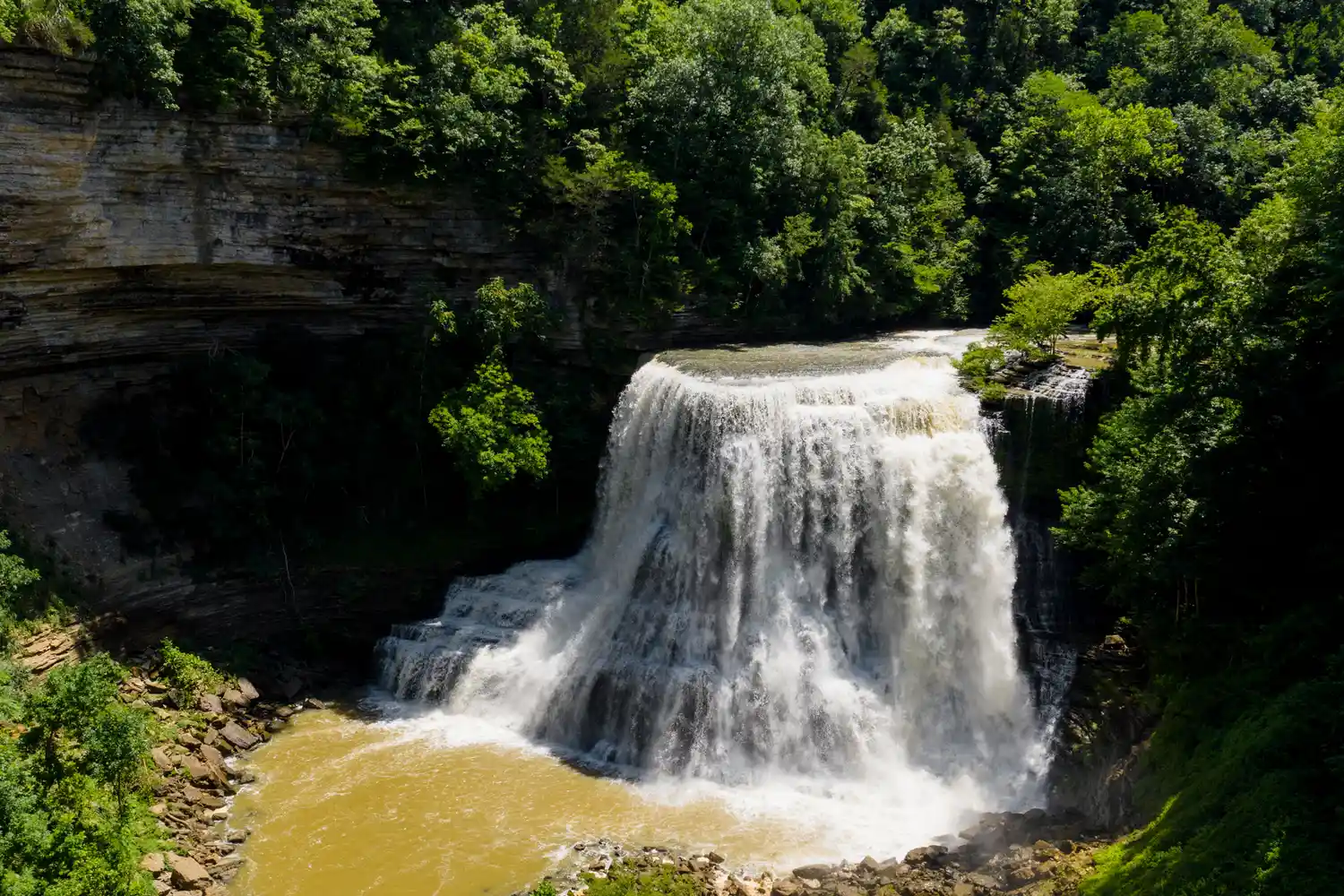 A powerful tiered waterfall at Burgess Falls State Park cascading into a pool below.