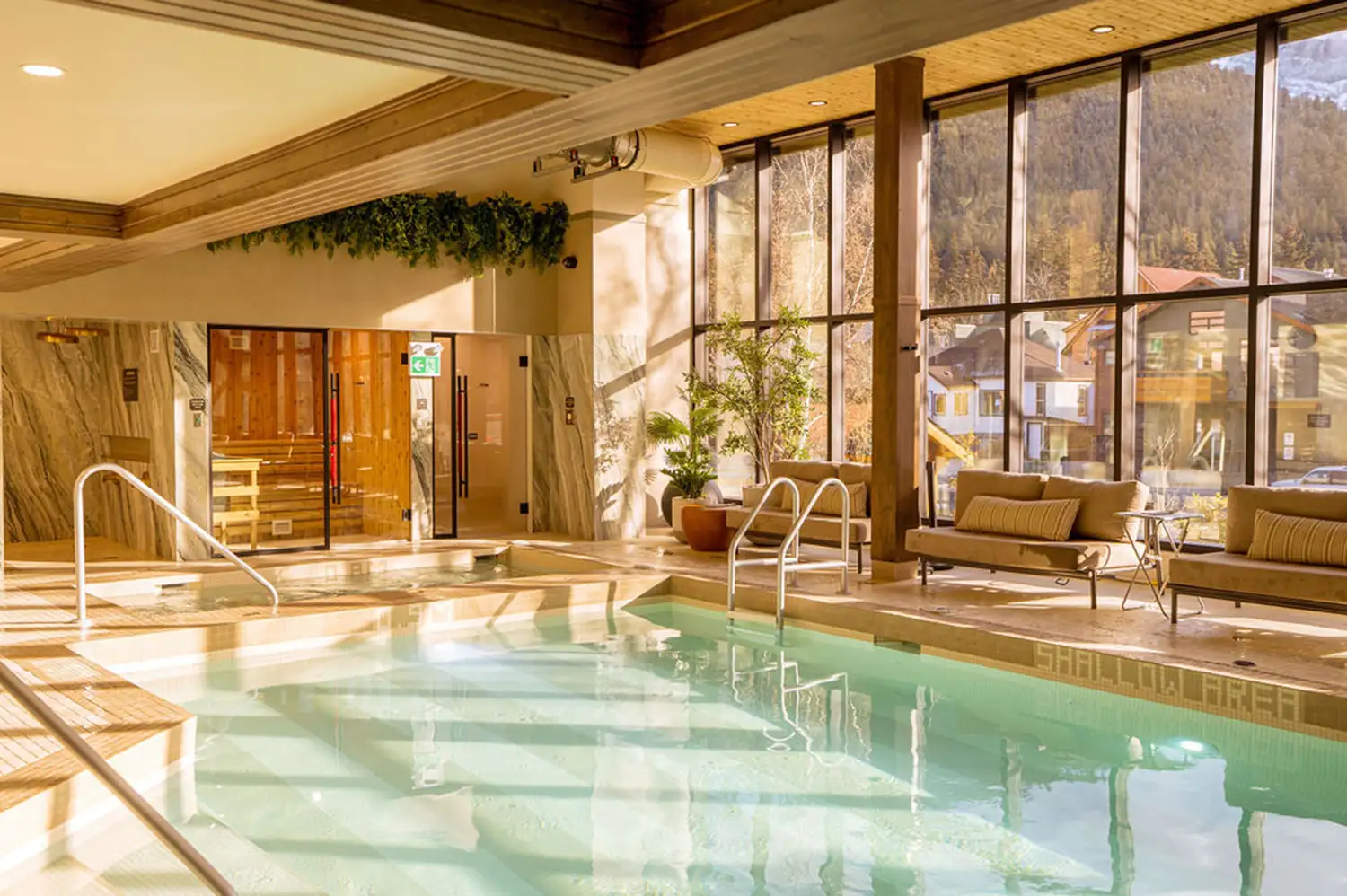 An indoor saltwater pool with large windows overlooking the mountainous terrain of Banff.