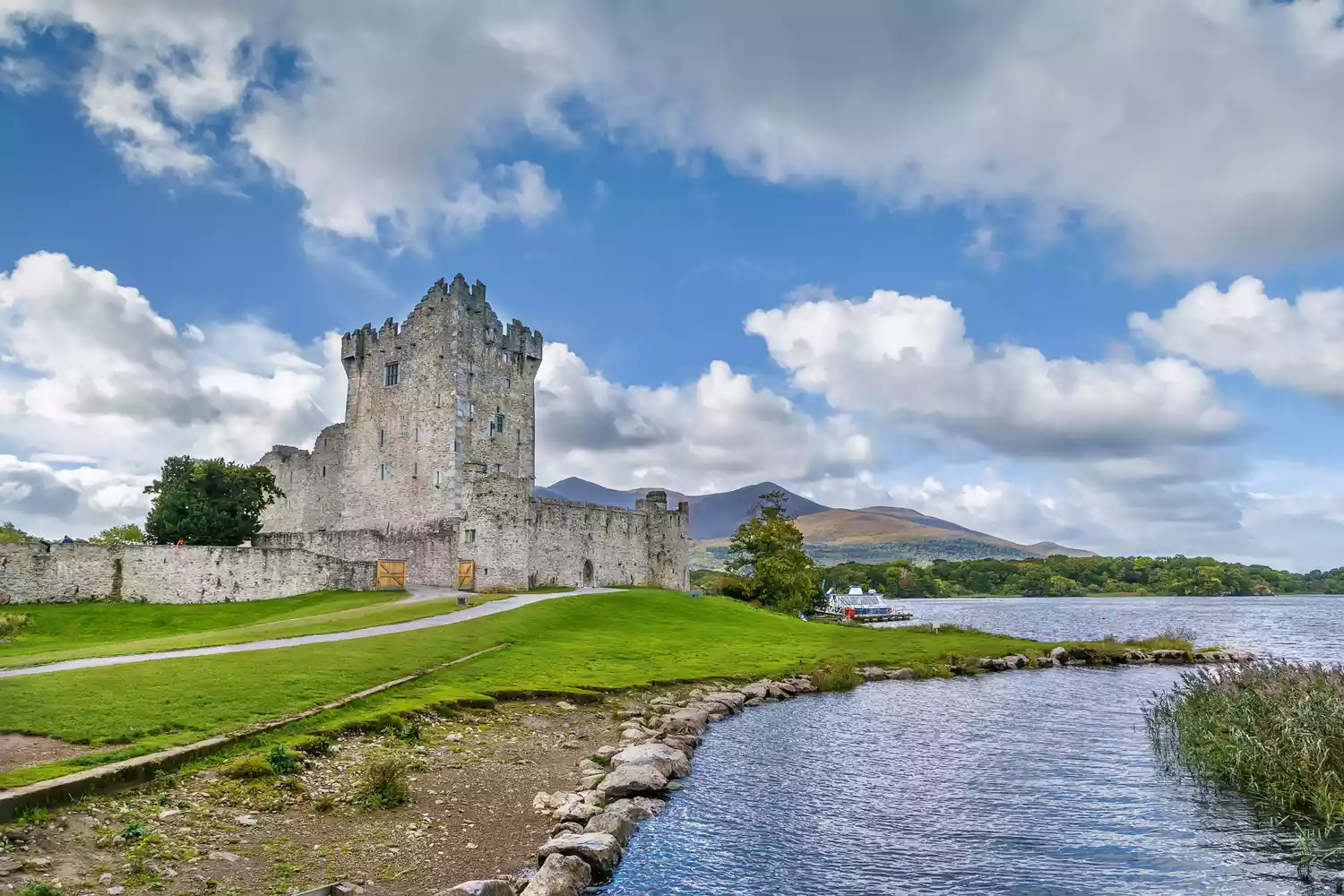 The stone tower of Ross Castle situated at the edge of a lake in Killarney National Park.