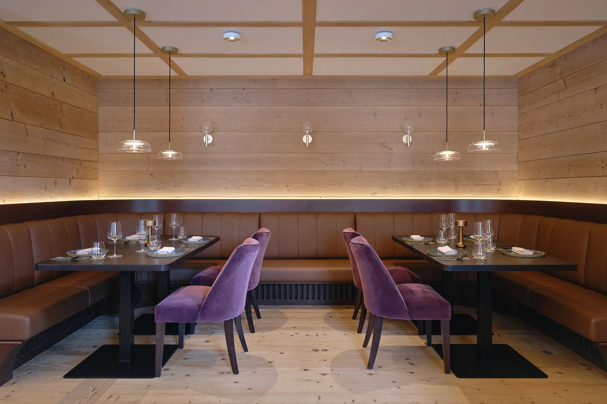 Interior of Restaurant Quell featuring leather bench seating, wooden walls, and modern purple accent chairs.