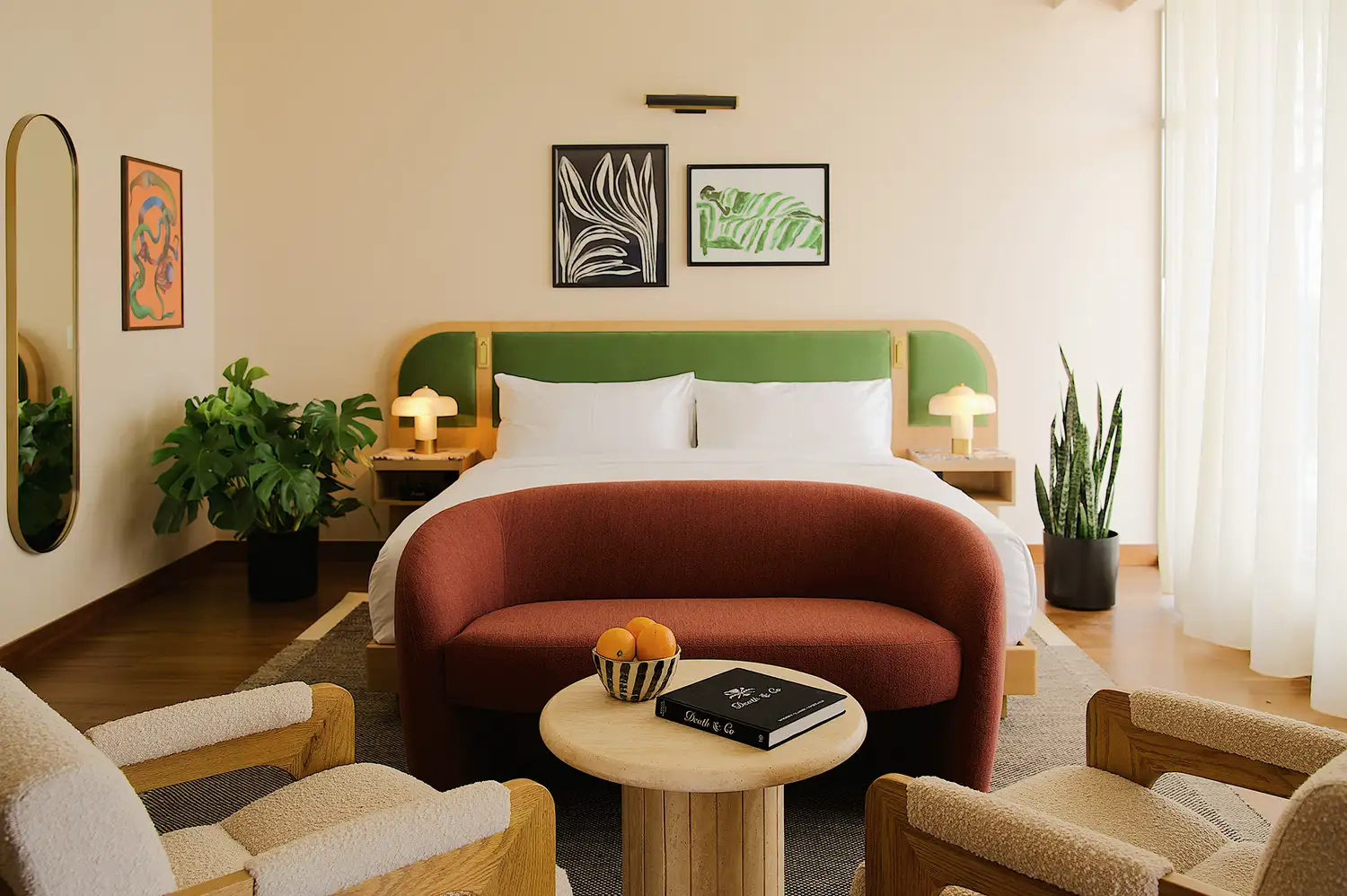 A stylish hotel room with a modern bed, deep blue accents, and curated indoor plants.