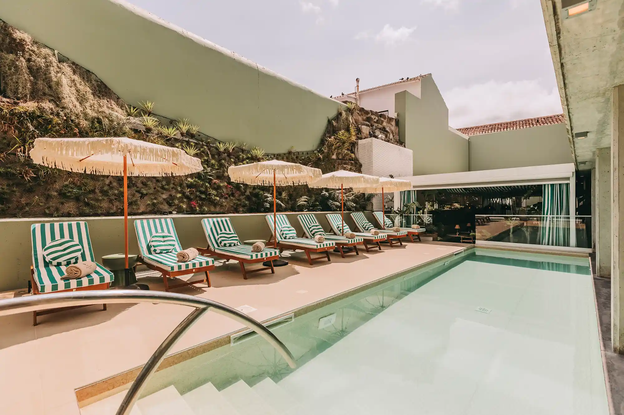Outdoor swimming pool at Torel Terra Brava with striped lounge chairs and views of local hills.