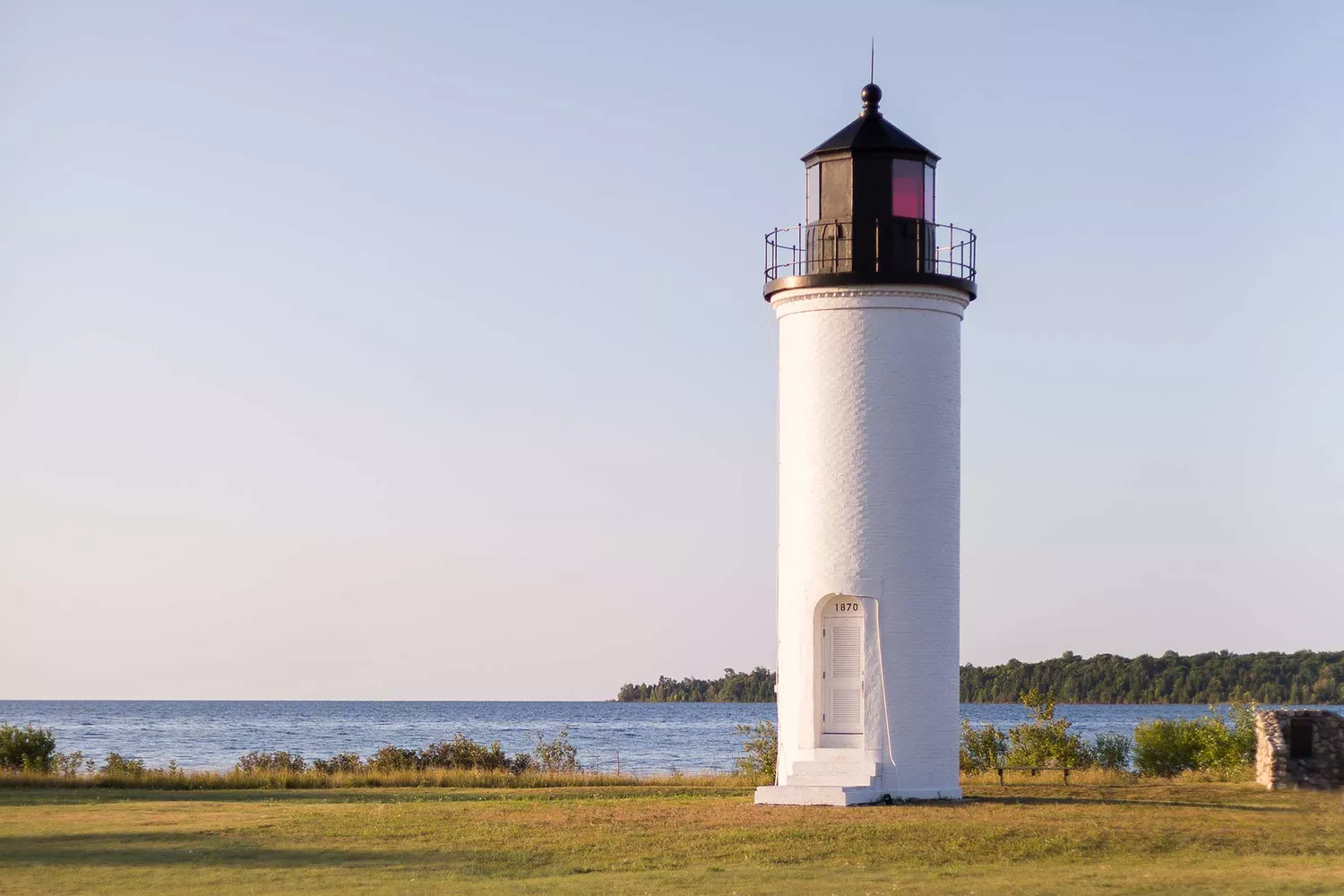 A white lighthouse standing on the rugged shore at St. James on Beaver Island.