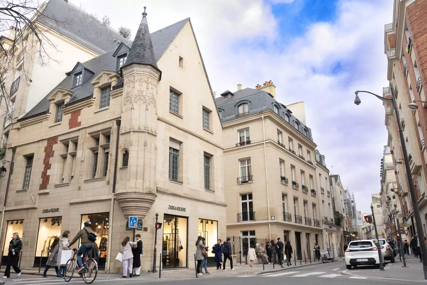 A narrow, charming shopping street in the Marais lined with boutiques and historic architecture.