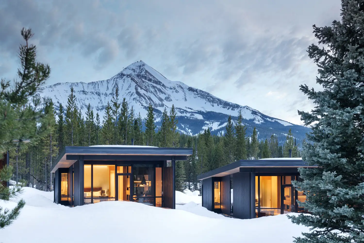 Modern luxury alpine cabins under a snowy peak in Big Sky Montana.