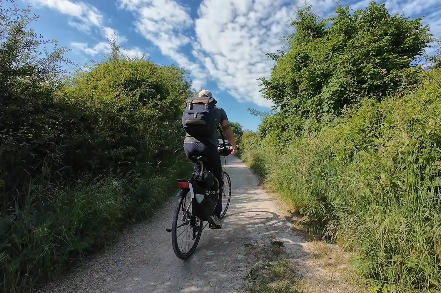 A cyclist navigating a tree-lined paved path in the rural Loire Valley area.