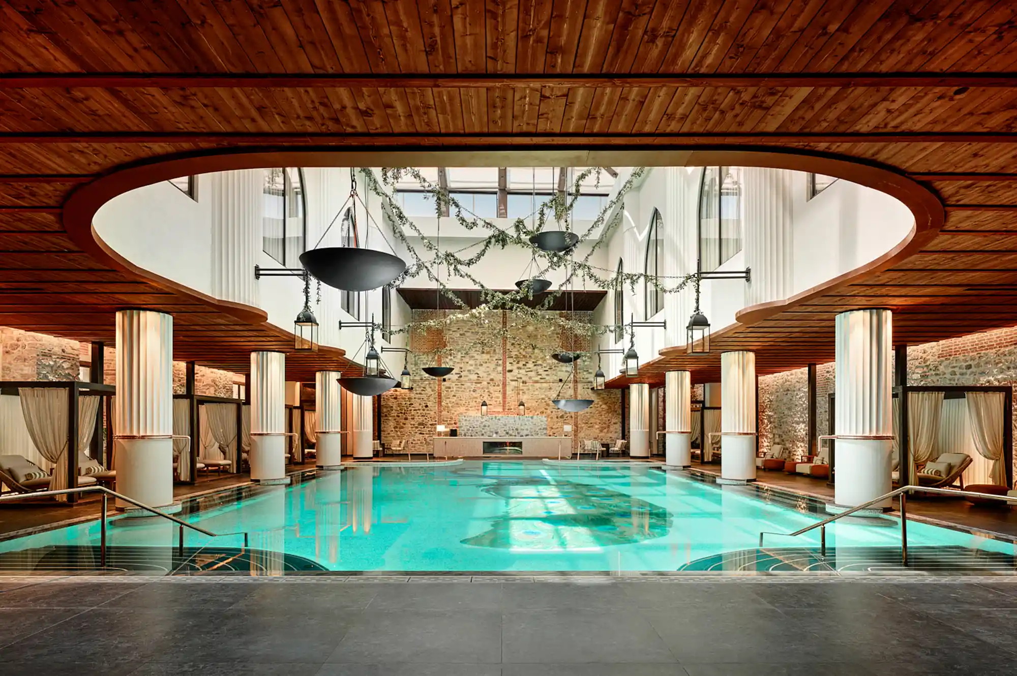 Indoor infinity pool at the Well+ Spa with wooden ceilings and atmospheric lighting.