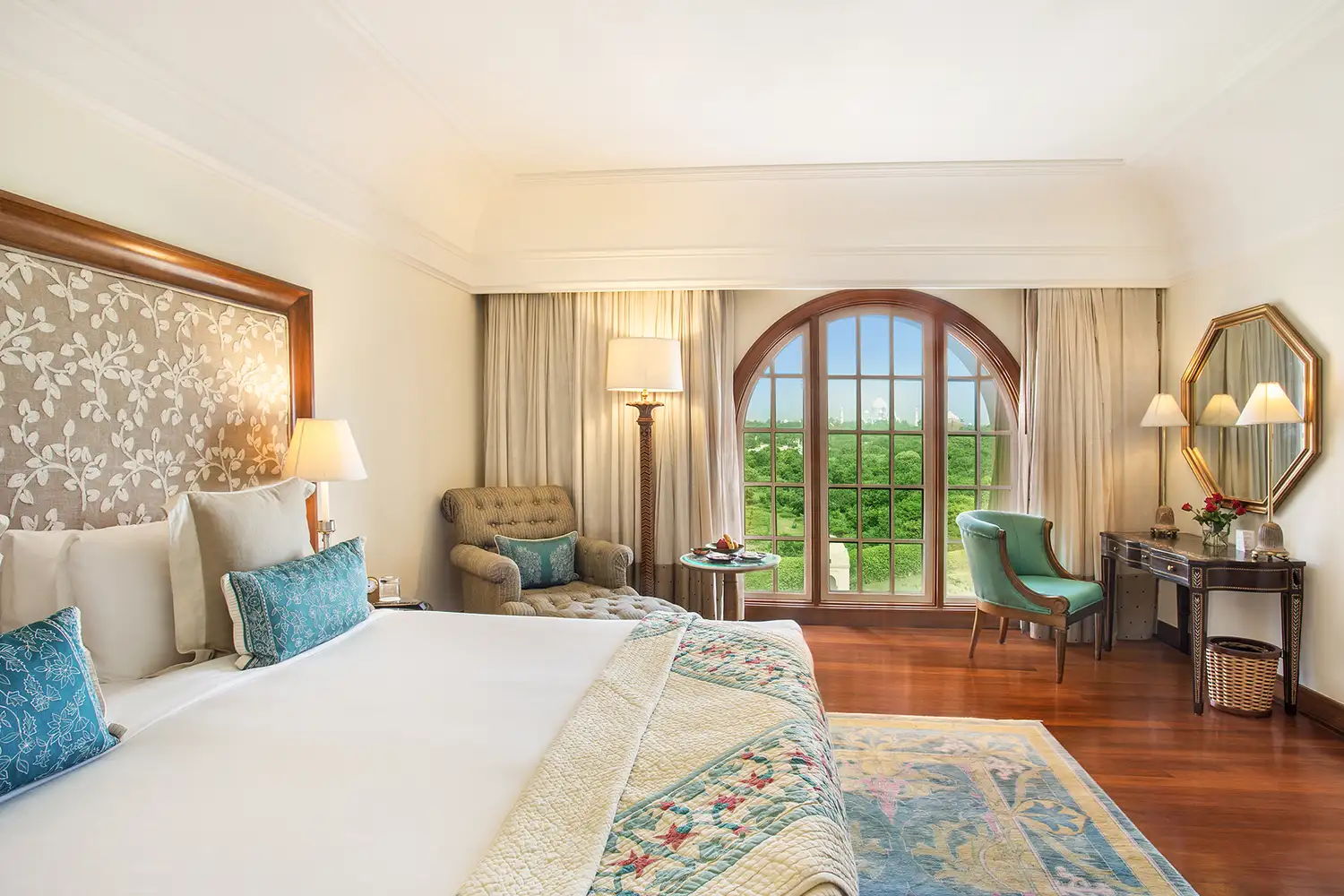 Luxury hotel suite at The Oberoi Amarvilas with a views of lush greenery through an arched window.