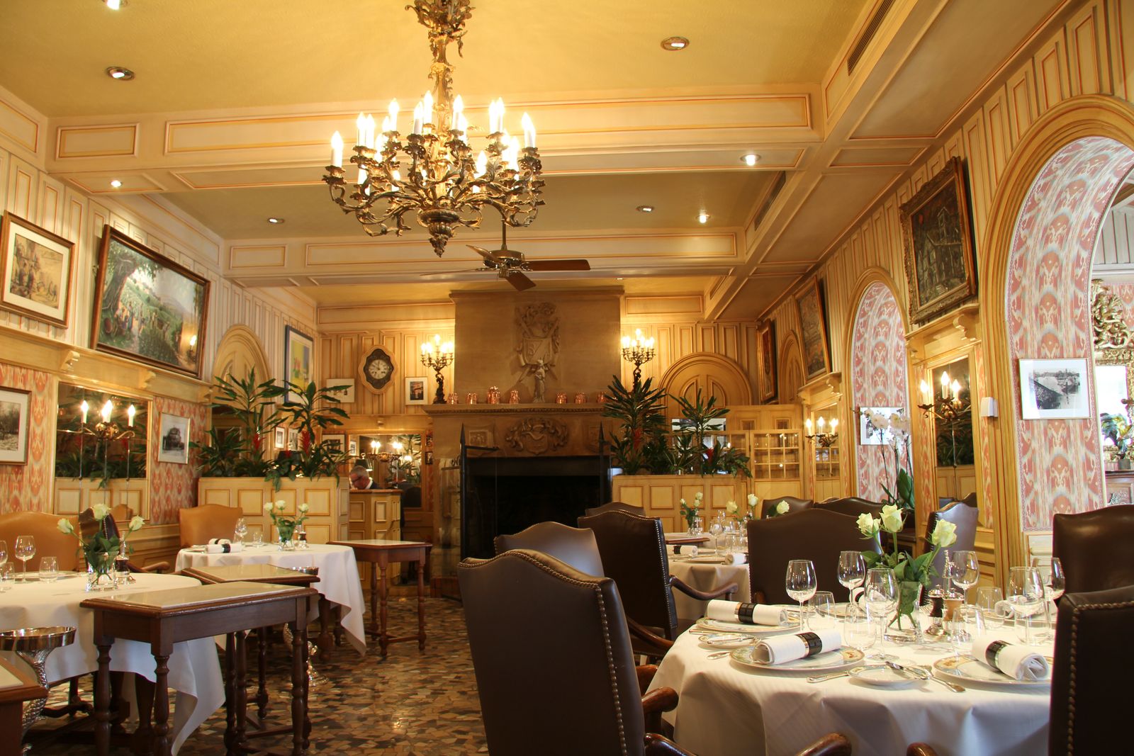 Elegant restaurant dining room with a chandelier and white tablecloths.