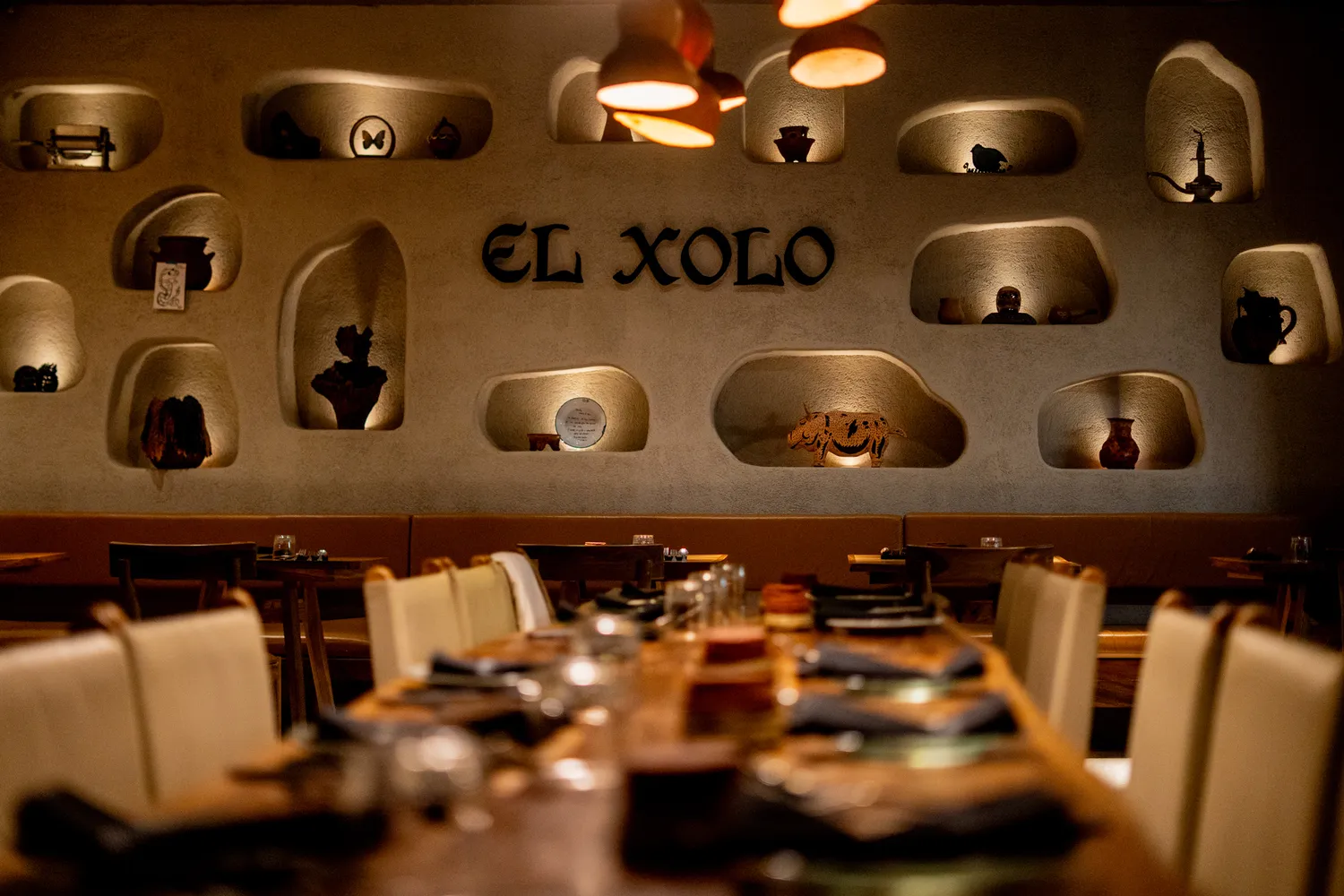 Interior design of El Xolo restaurant with wooden tables and warm lighting.