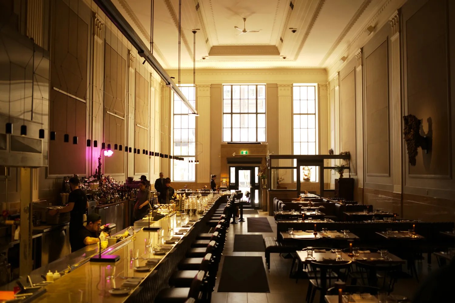 The contemporary and upscale interior of Riviera restaurant with high ceilings and a prominent bar.