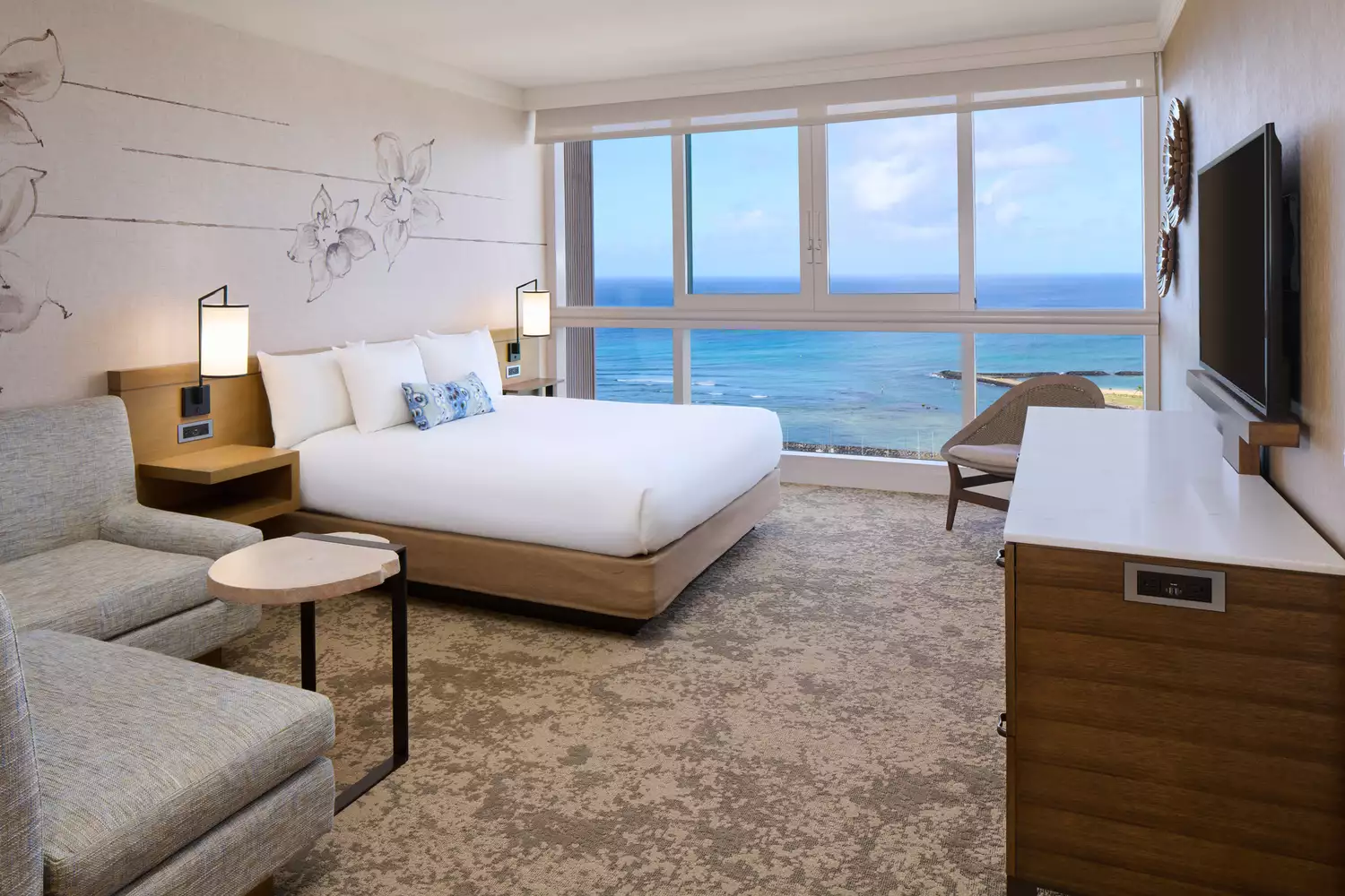 A high-floor oceanfront suite at Prince Waikiki with floor-to-ceiling windows overlooking the water.