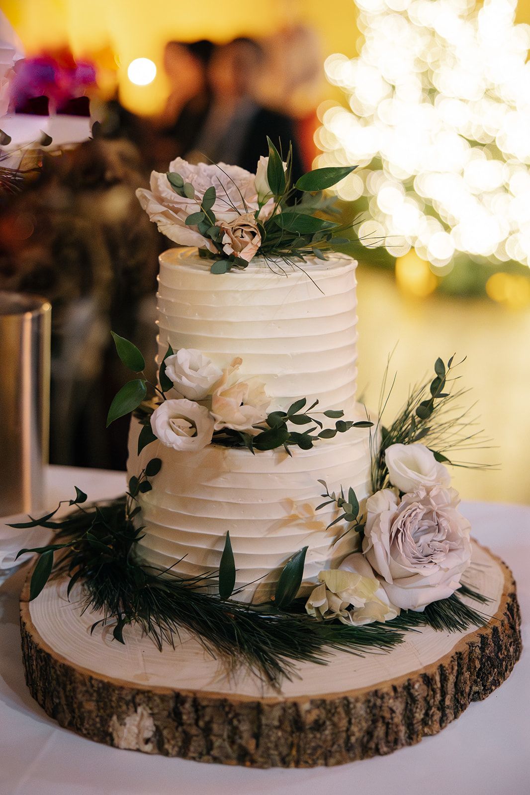A three-tier wedding cake decorated with fresh pink and white roses.
