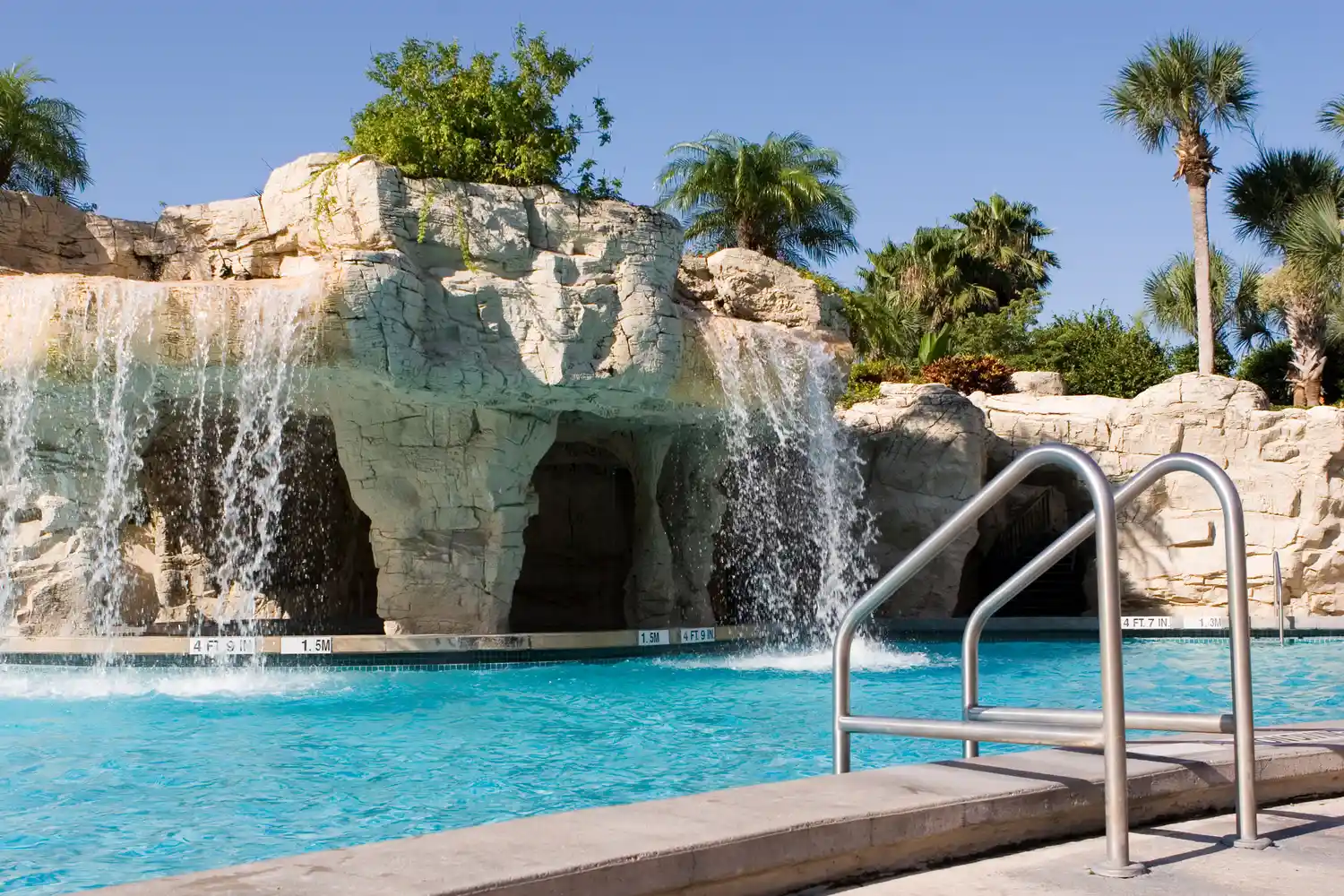 A luxury resort pool area featuring unique rock formations and waterfall landscaping.