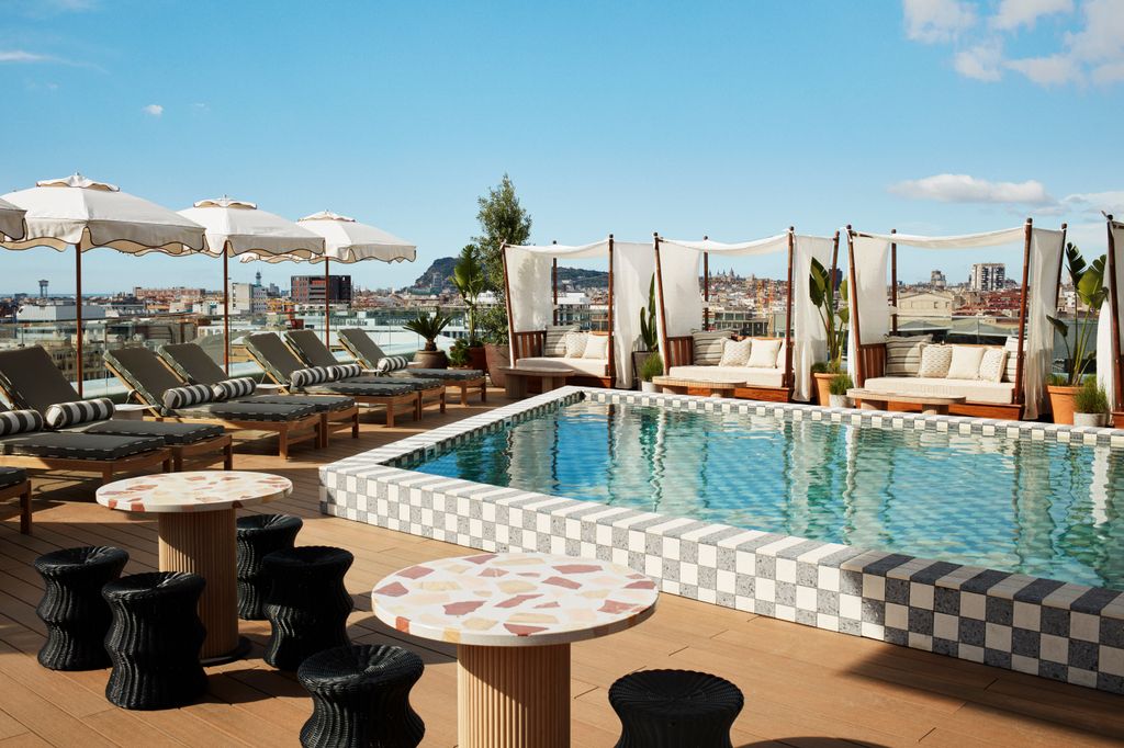 Rooftop pool deck at The Hoxton Poblenou with views of Barcelona city skyline.