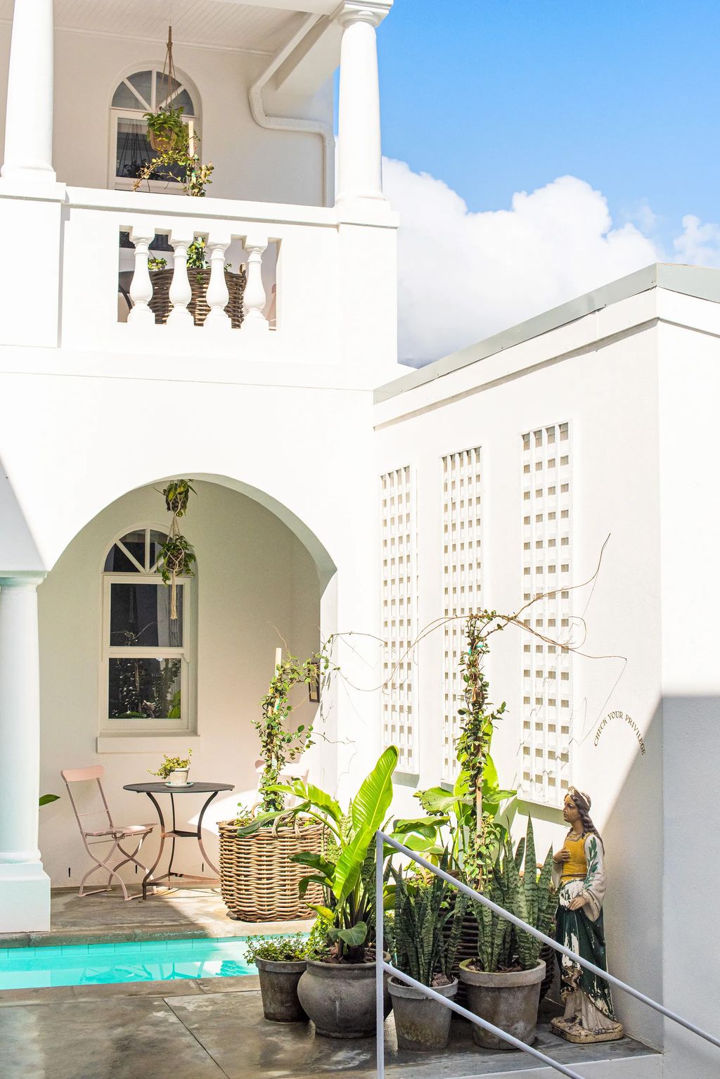 An eclectic hotel lounge with large arched windows framing Table Mountain and vintage-style decor.