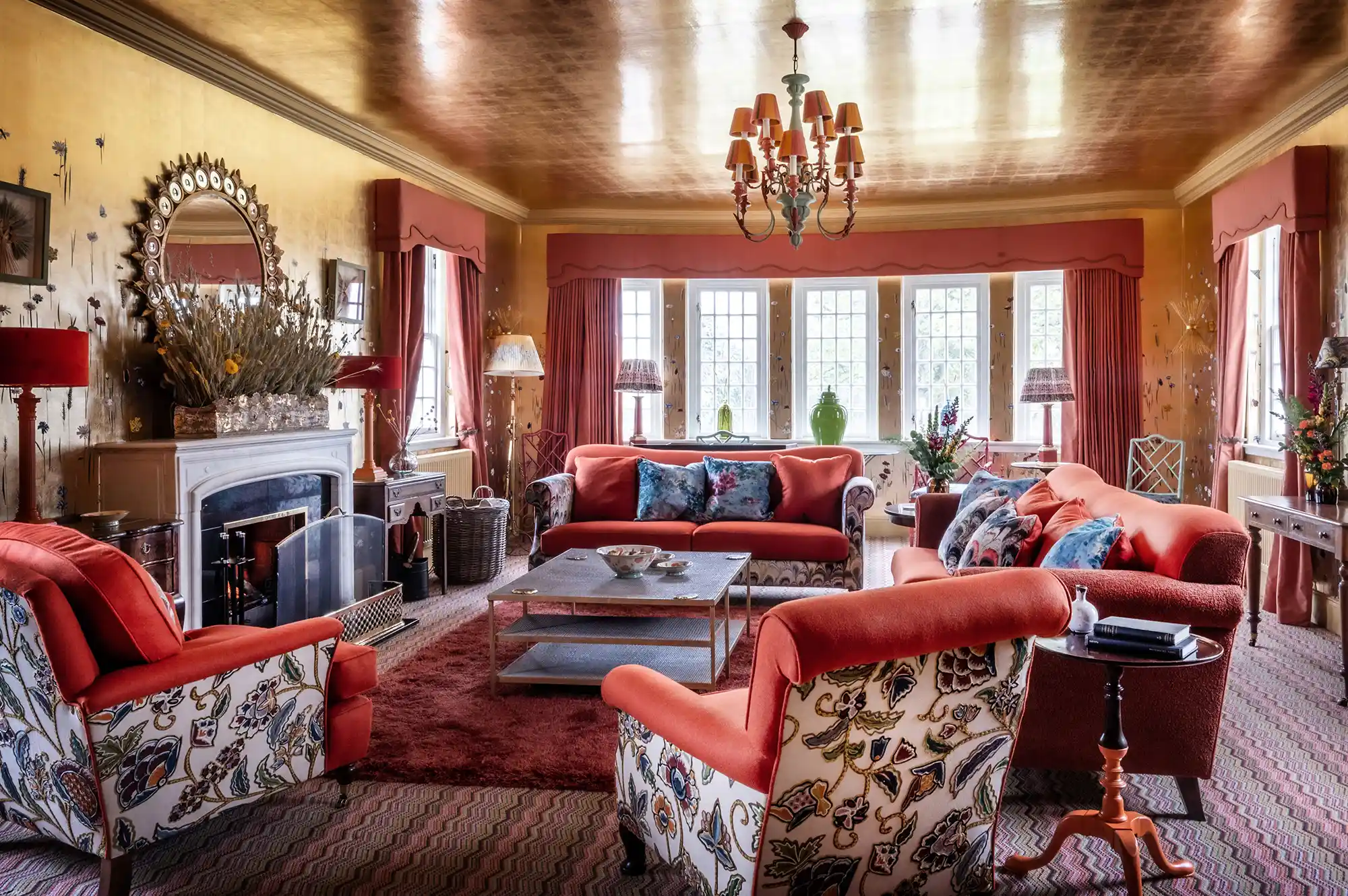 A sophisticated hotel lounge with plush seating, a fireplace, and large windows looking out onto a green landscape.