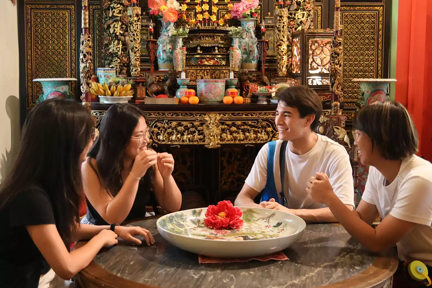 A group of people dining together in a richly decorated traditional Peranakan mansion interior.