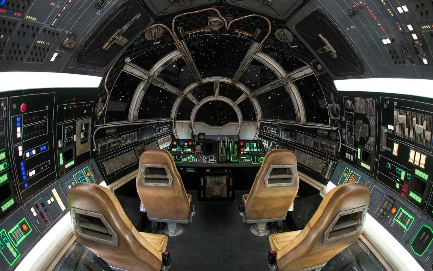 The interior cockpit of the Millennium Falcon with glowing orange lights and flight controls.