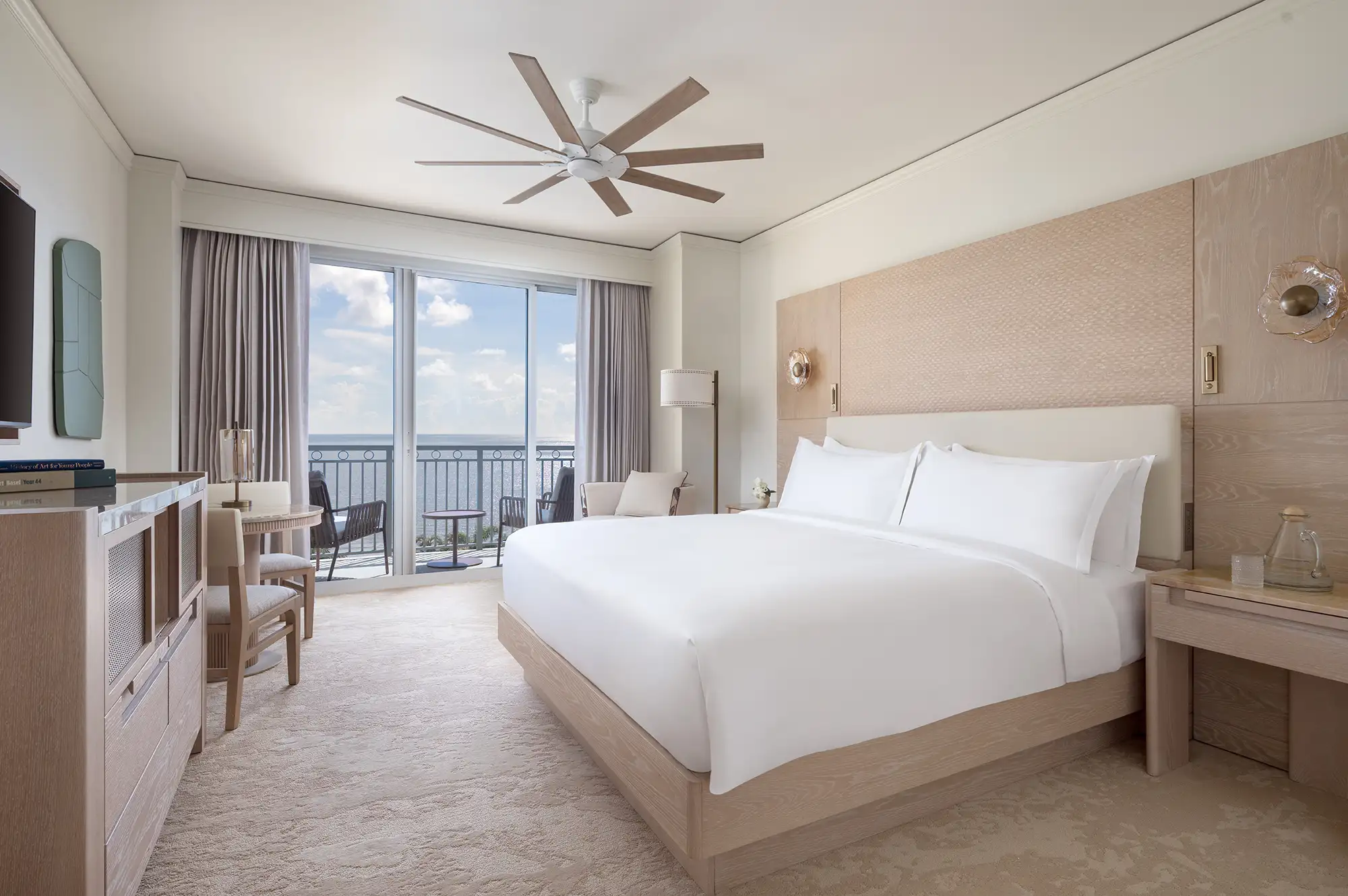 A modern guest room at Ritz-Carlton Key Biscayne featuring a desk, plush bedding, and a balcony with Atlantic ocean views.