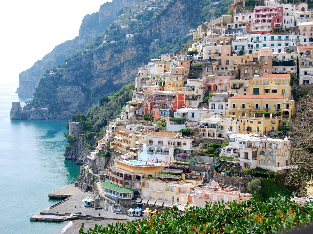 Colorful houses built into the steep mountainsides overlooking the blue sea on the Amalfi Coast.