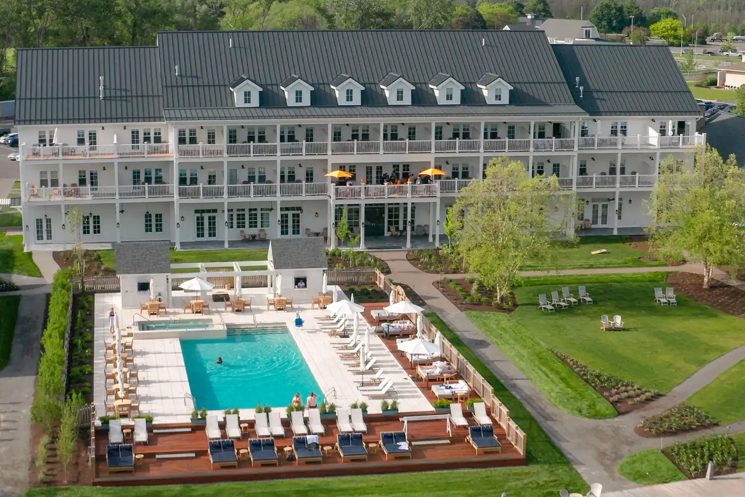 Aerial vista of a luxury lakefront hotel with a pool and lush landscaping in the Finger Lakes.