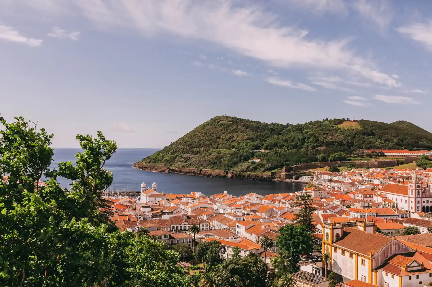 Scenic panoramic view of the red-roofed buildings of Angra do Heroísmo and the Atlantic Ocean.