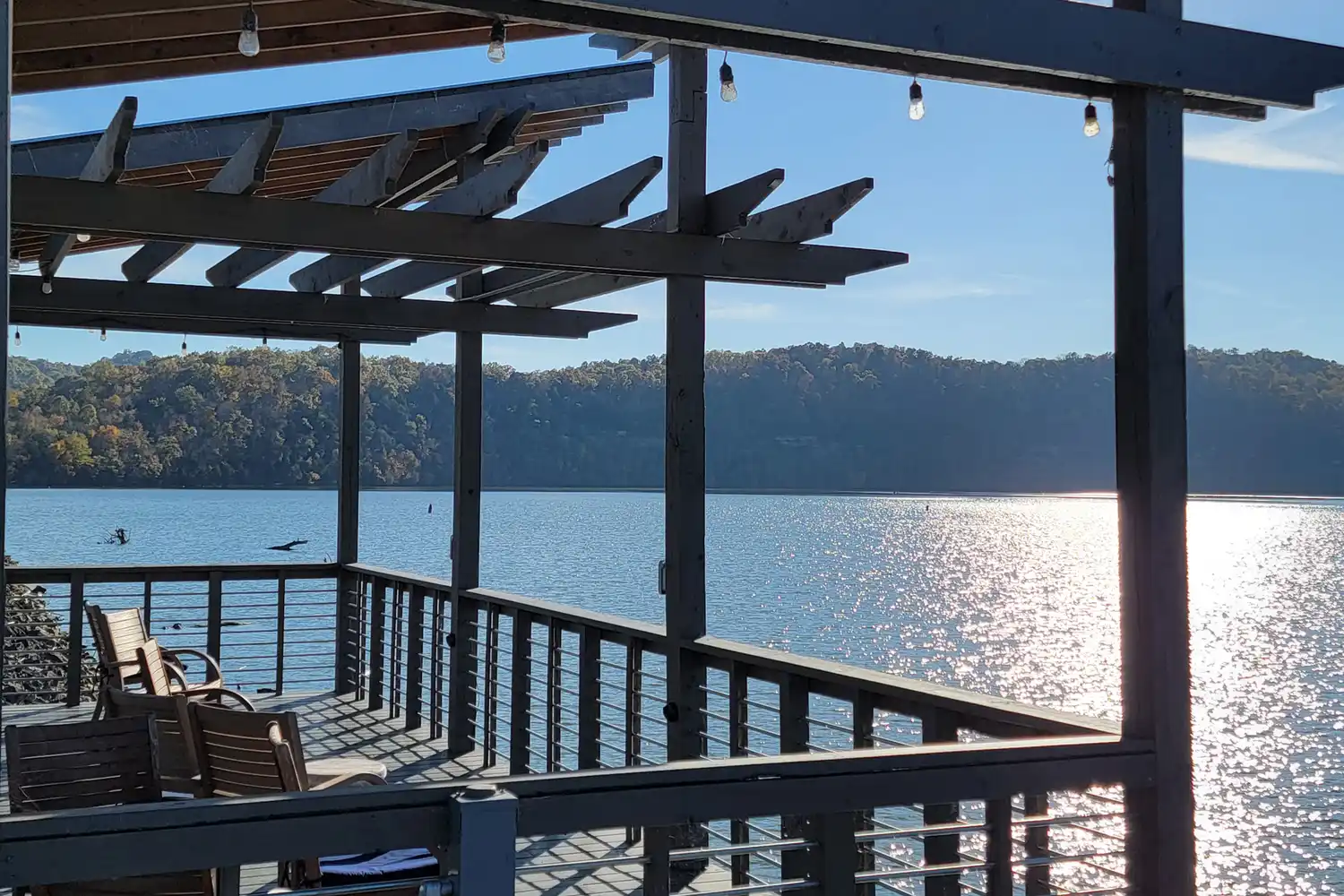 A wooden deck overlooking a peaceful lake surrounded by forested hills in Cookeville.