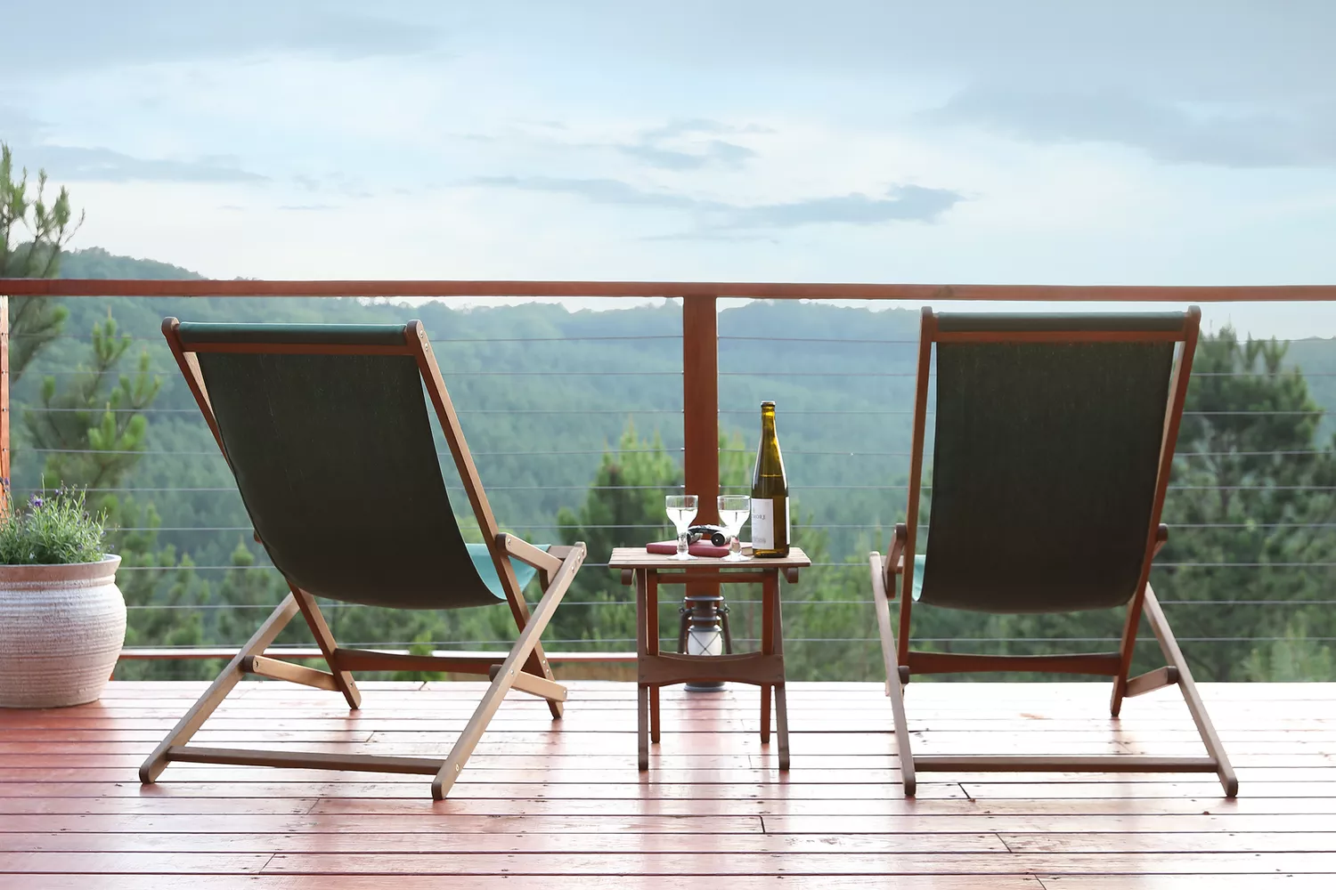 Two lounge chairs facing the rolling hills on a high-elevation wooden deck.