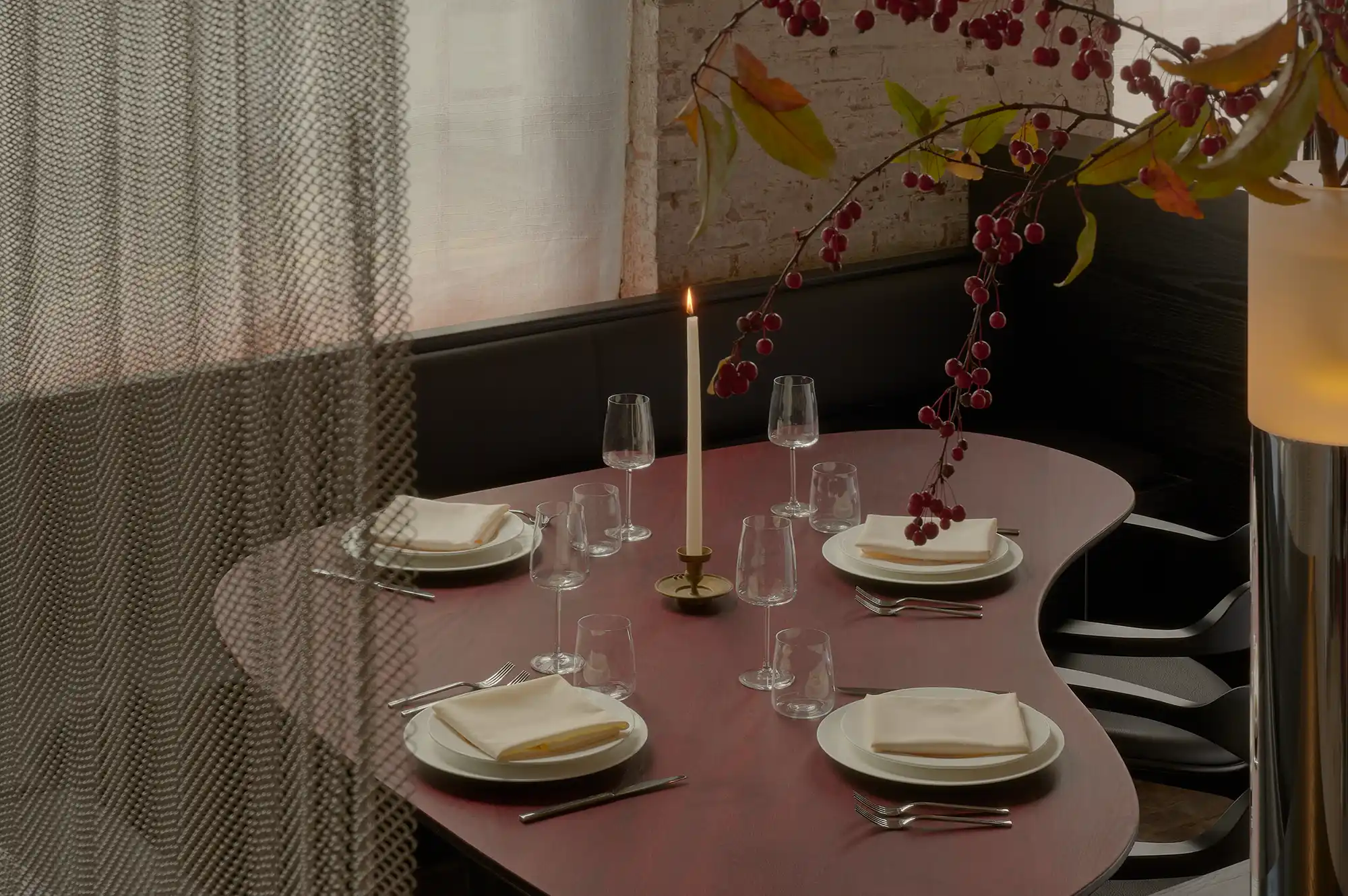 A set dining table with wine glasses and candles at the Ambos Hudson restaurant.