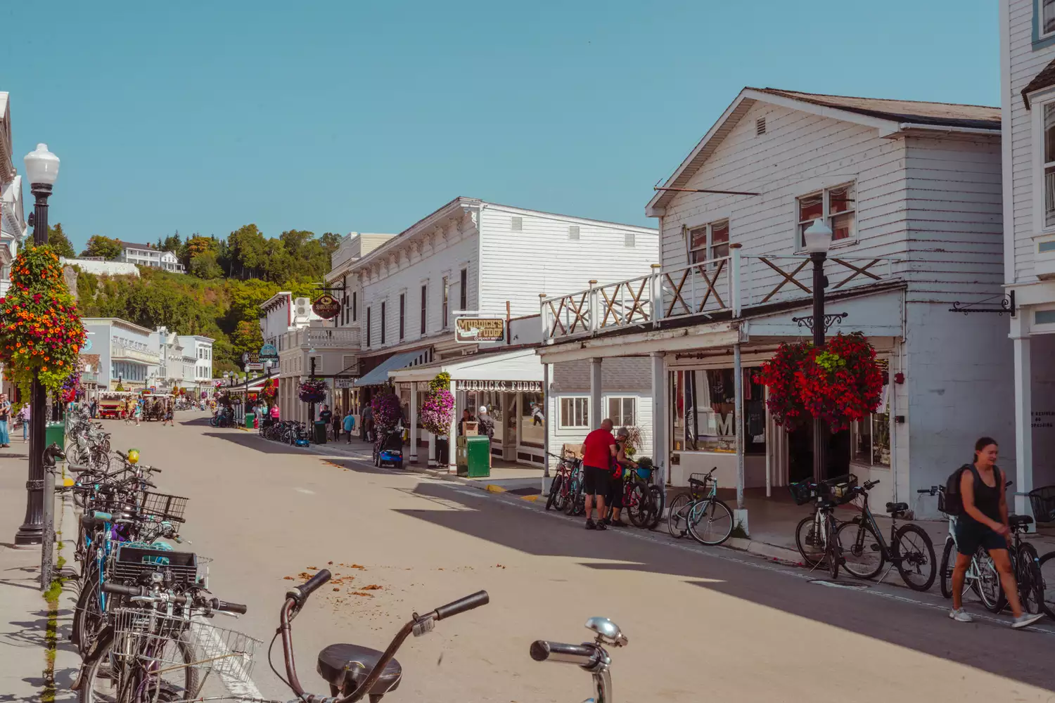 Downtown Mackinac Island featuring historic storefronts and horse-drawn carriages.