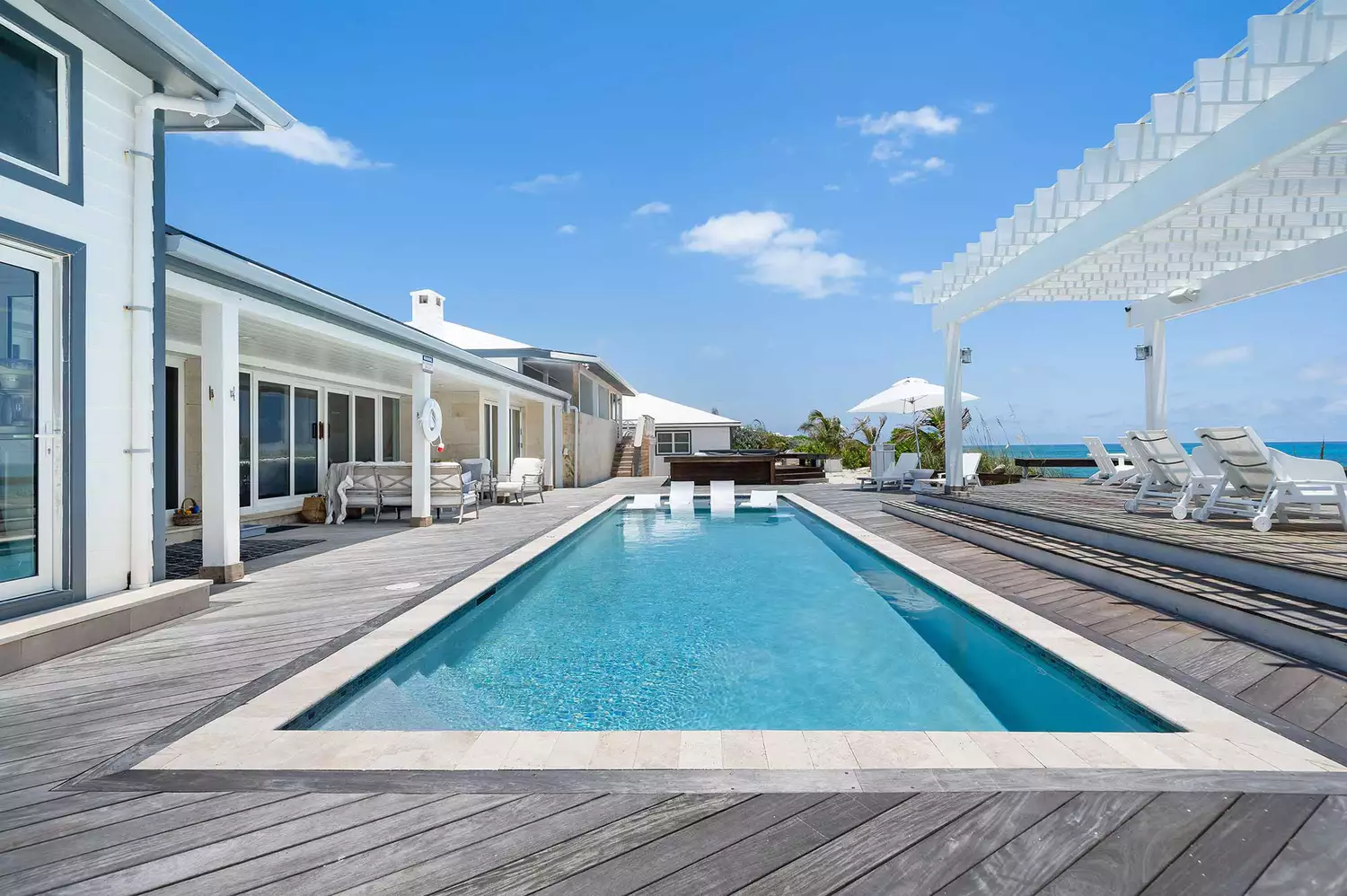 A modern infinity-edge pool deck overlooking the ocean at a private resort.