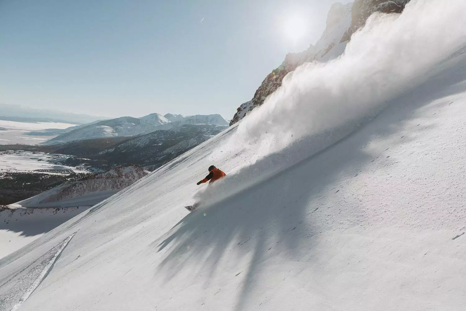 A snowboarder carving down a steep, snow-covered face at Mammoth Mountain Resort.