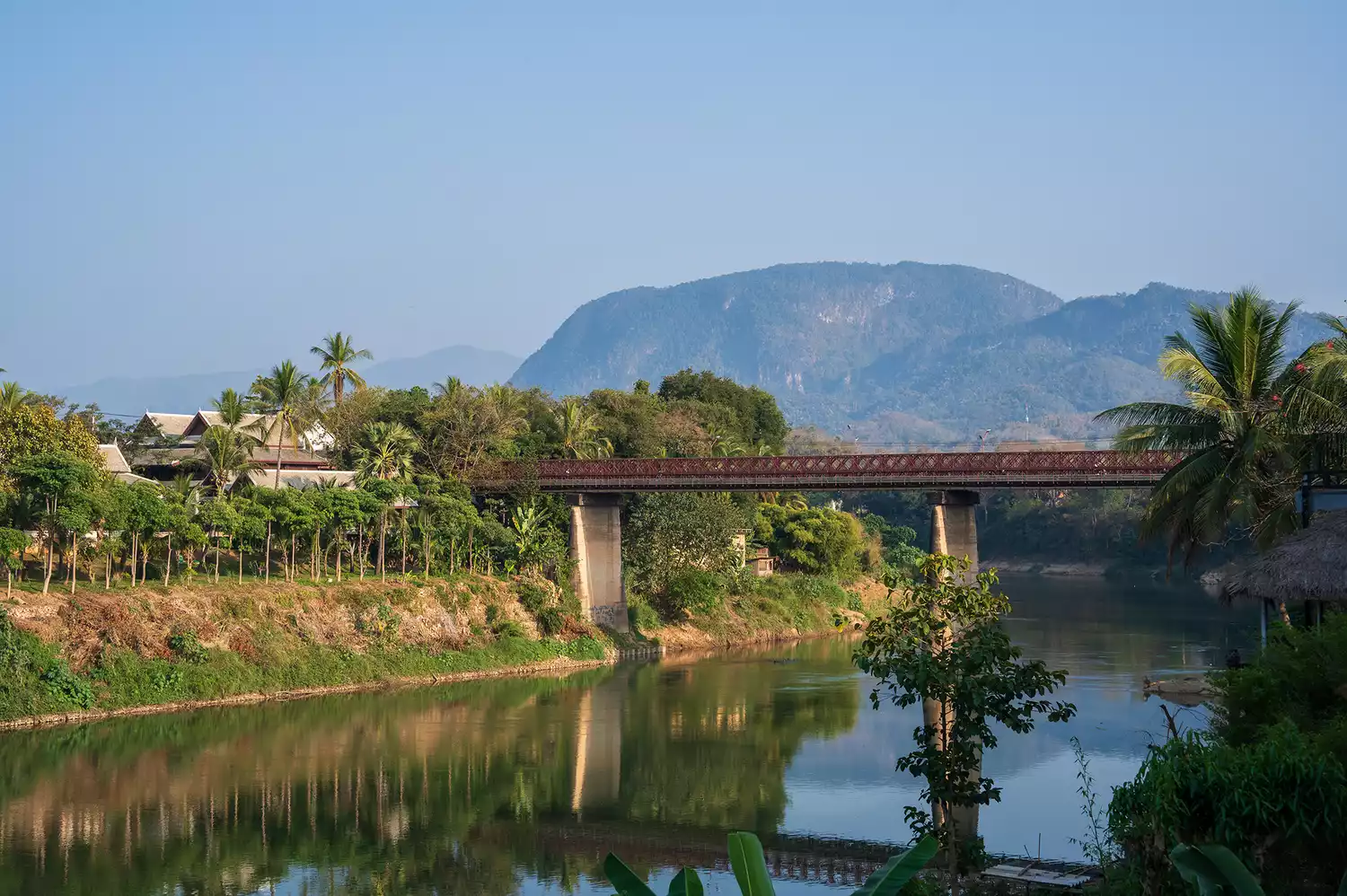 A wide view of the Nam Khan River flowing through the trees in Luang Prabang, Laos.